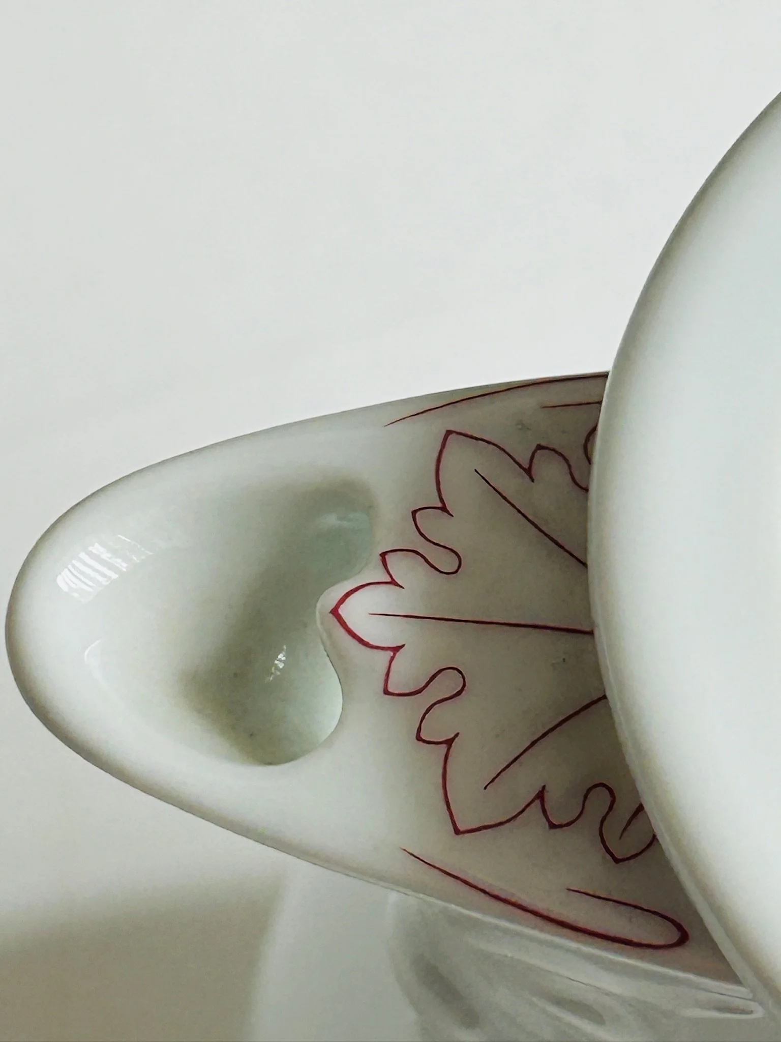 Detail of the spout and lid from above, showing the shaped pouring lip and floral leaf decoration.