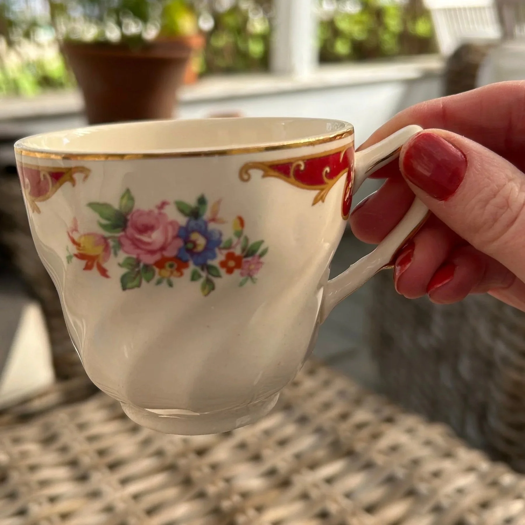 Cup held outdoors with sunlight showing translucency and gold detailing