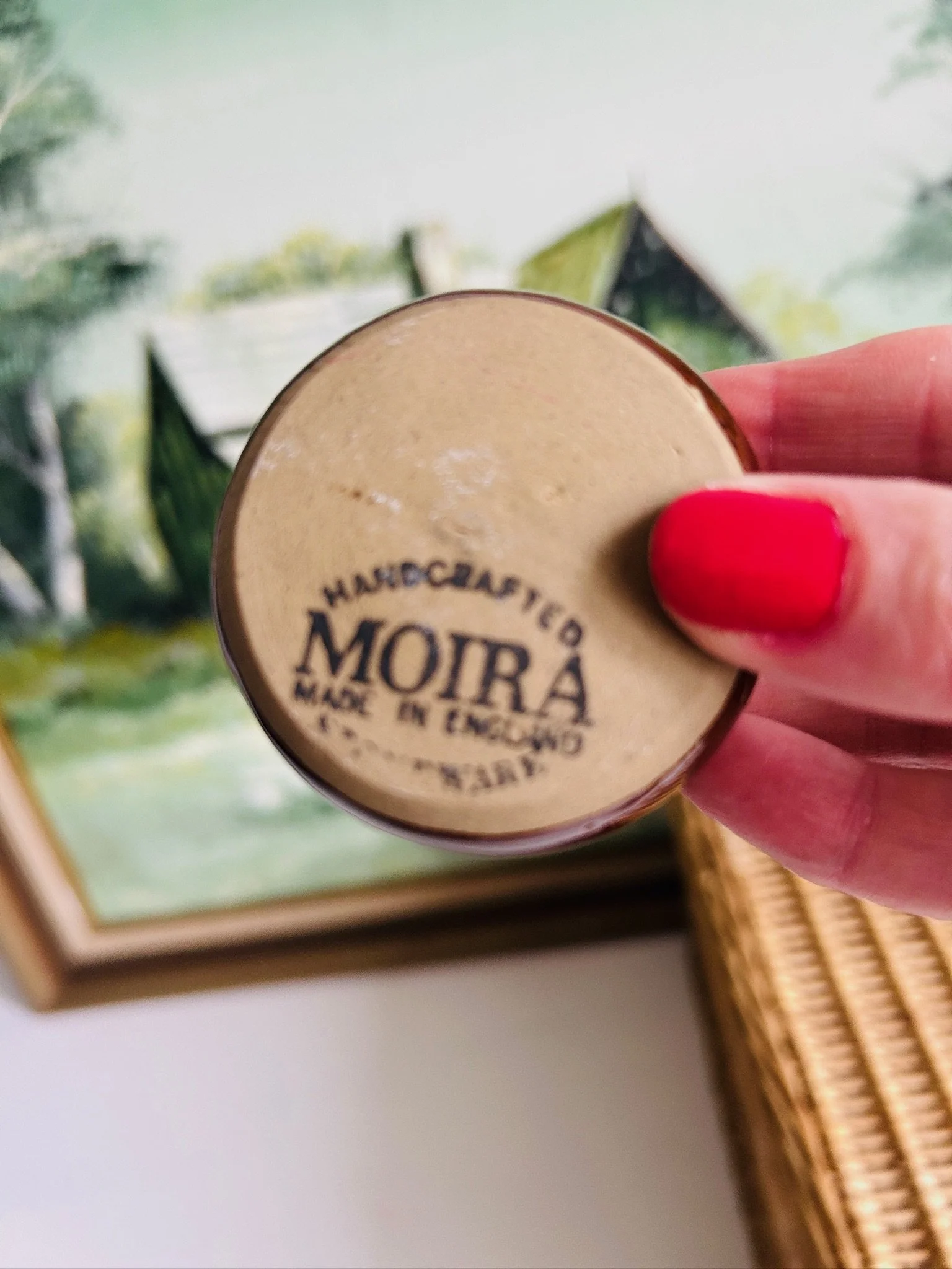 Underside of the pottery salt cellar held in hand, highlighting the impressed and stamped base mark