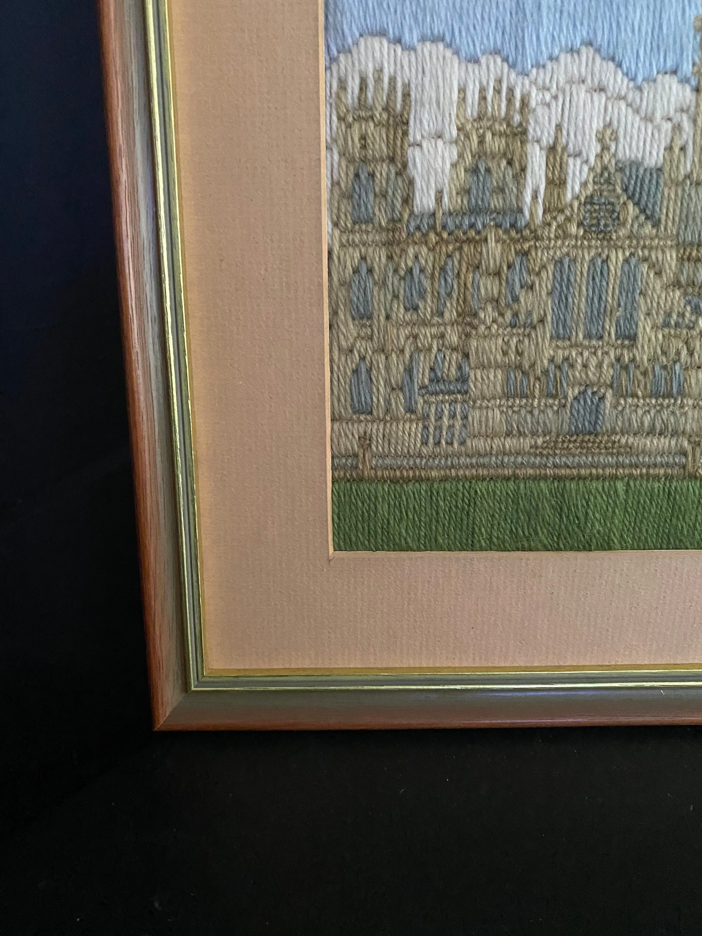 Close-up of the lower corner of the frame showing matting, stitched lawn, and frame finish