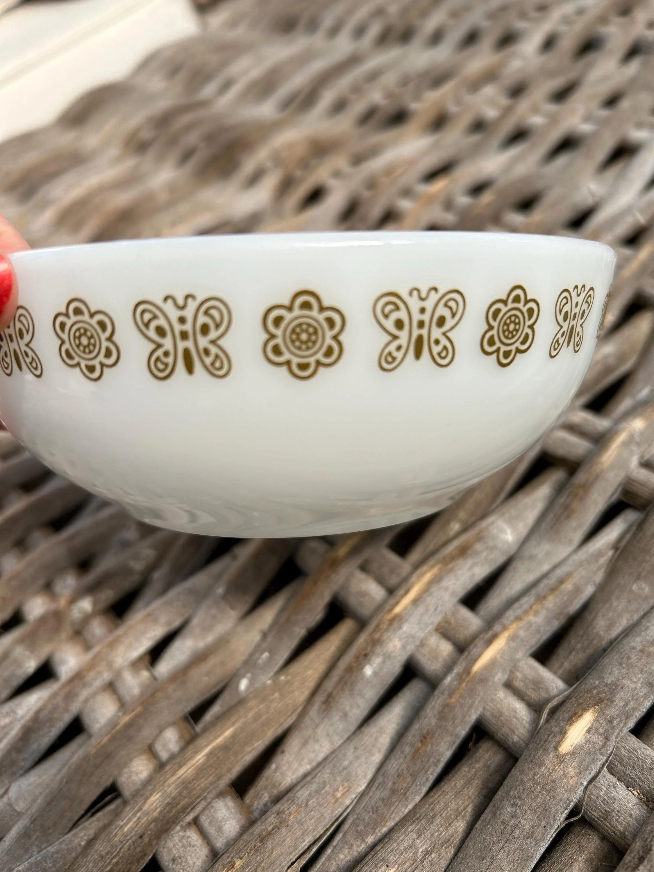 Close-up of khaki floral and butterfly pattern repeating around the bowl