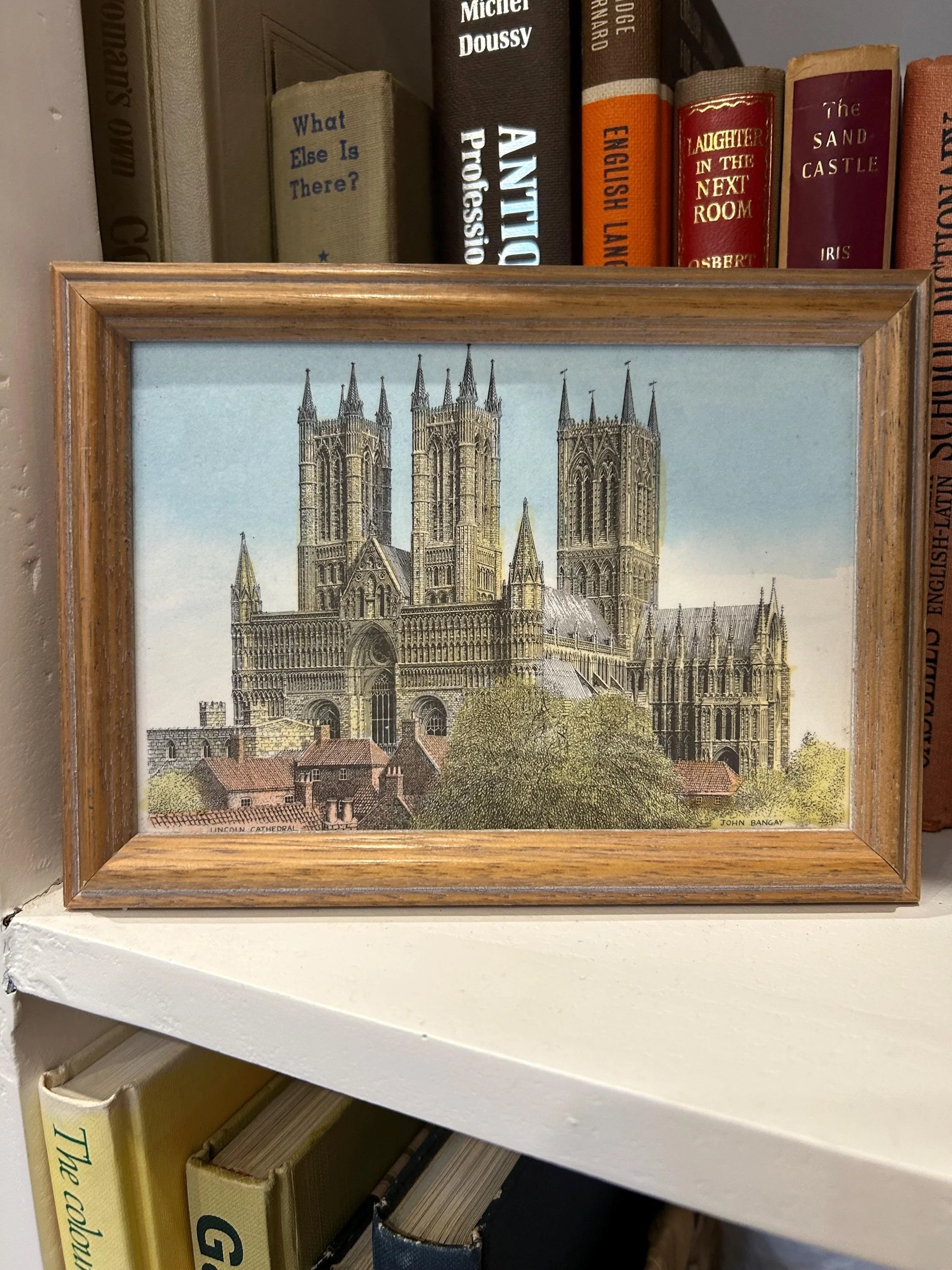 Framed piece shown on bookshelf with vintage books