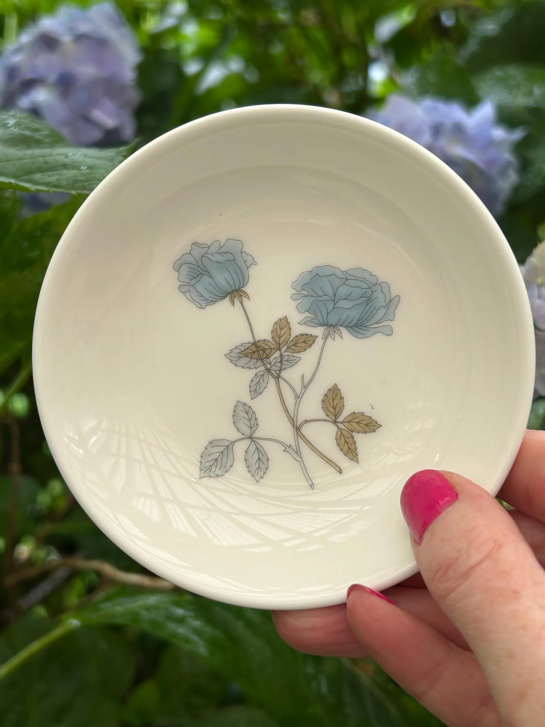 Hand-held view inside the dish showing the blue rose motif and smooth white glaze