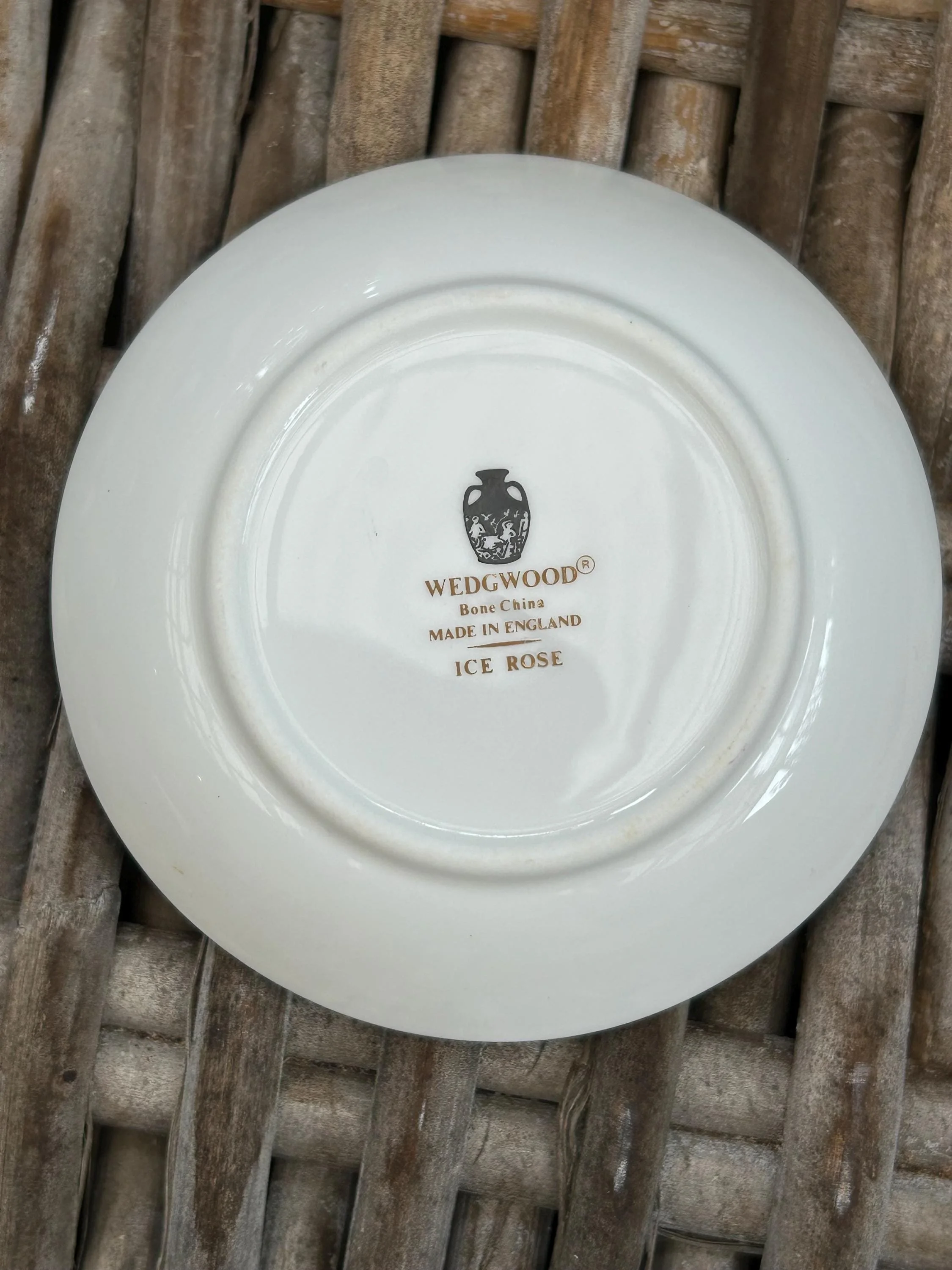 Underside of the dish resting on a wicker surface, showing the Wedgwood backstamp
