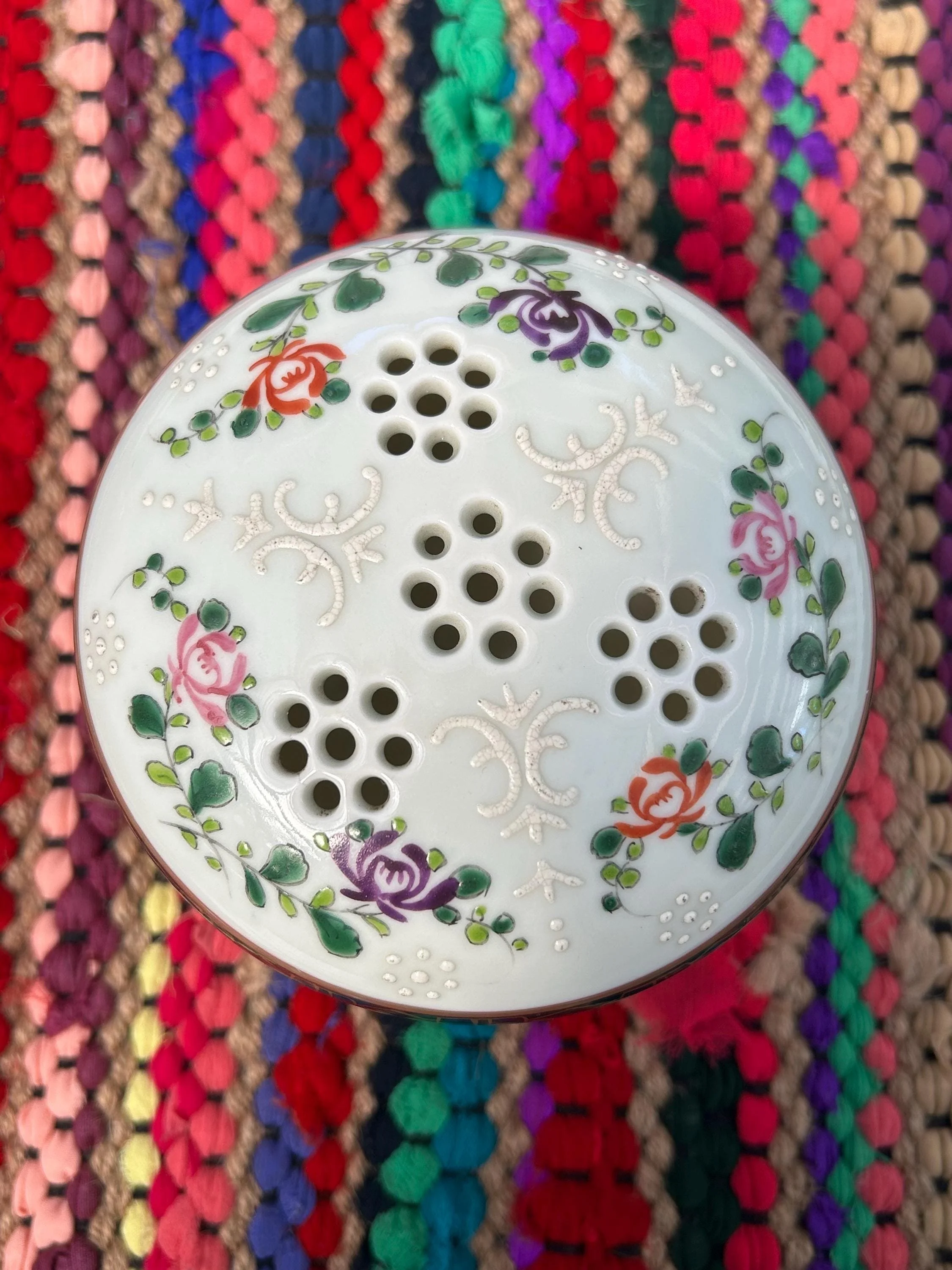 Top-down view of perforated lid with hand-painted roses and enamel dots