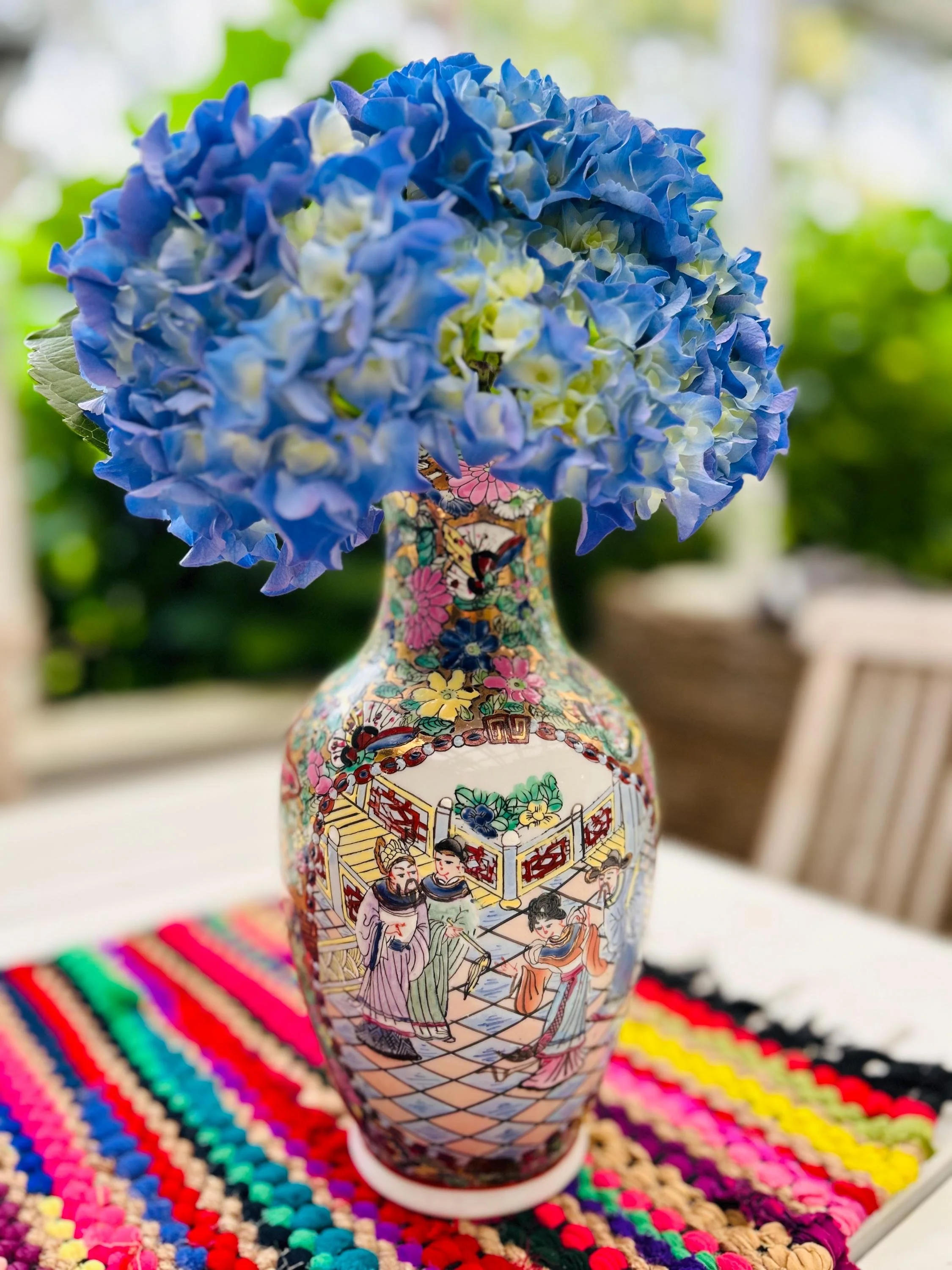 Vase styled with blue hydrangeas on a patio setting, showing full front view