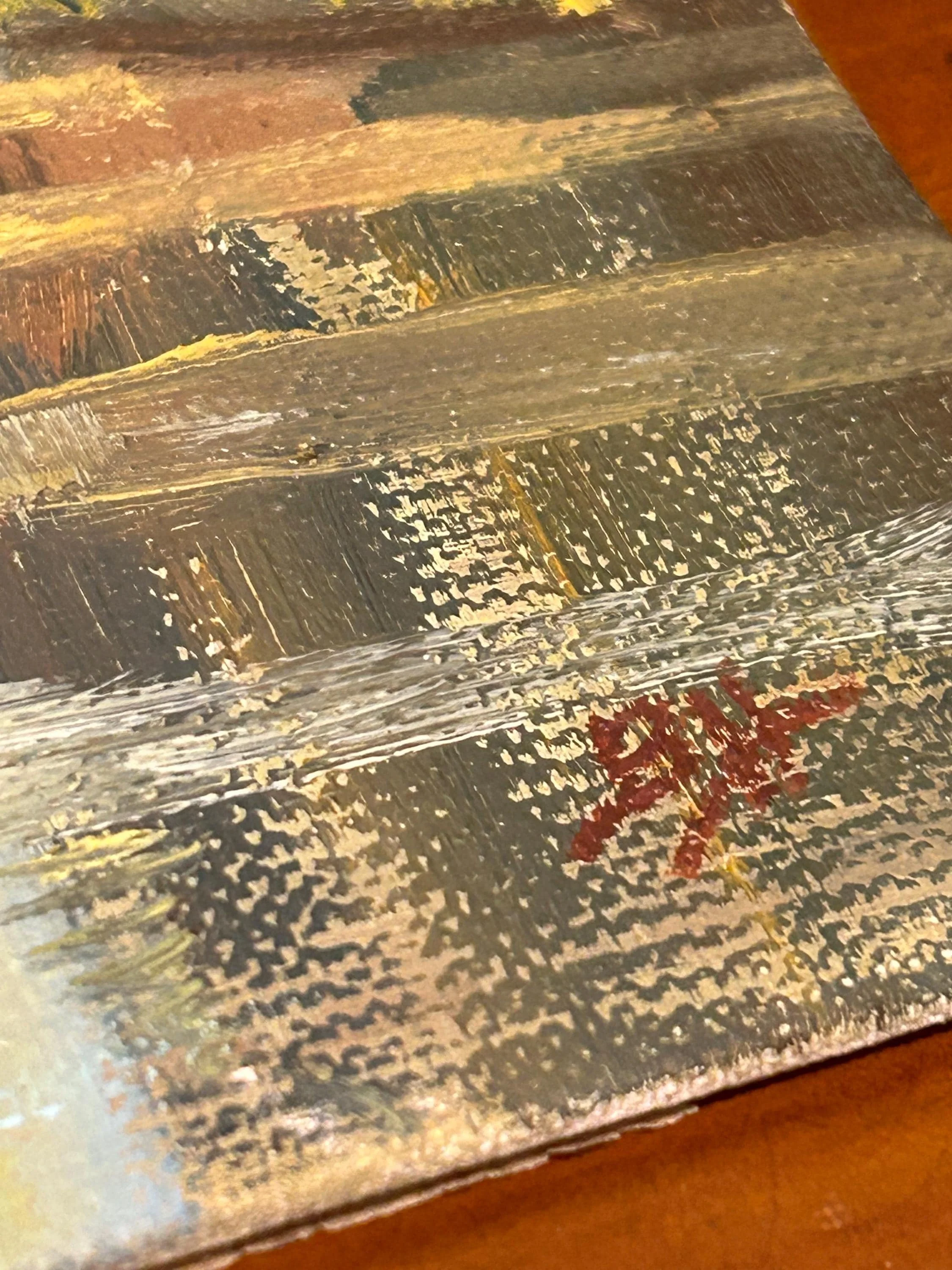 Close-up of artist's signature with brushstroke texture and canvas weave