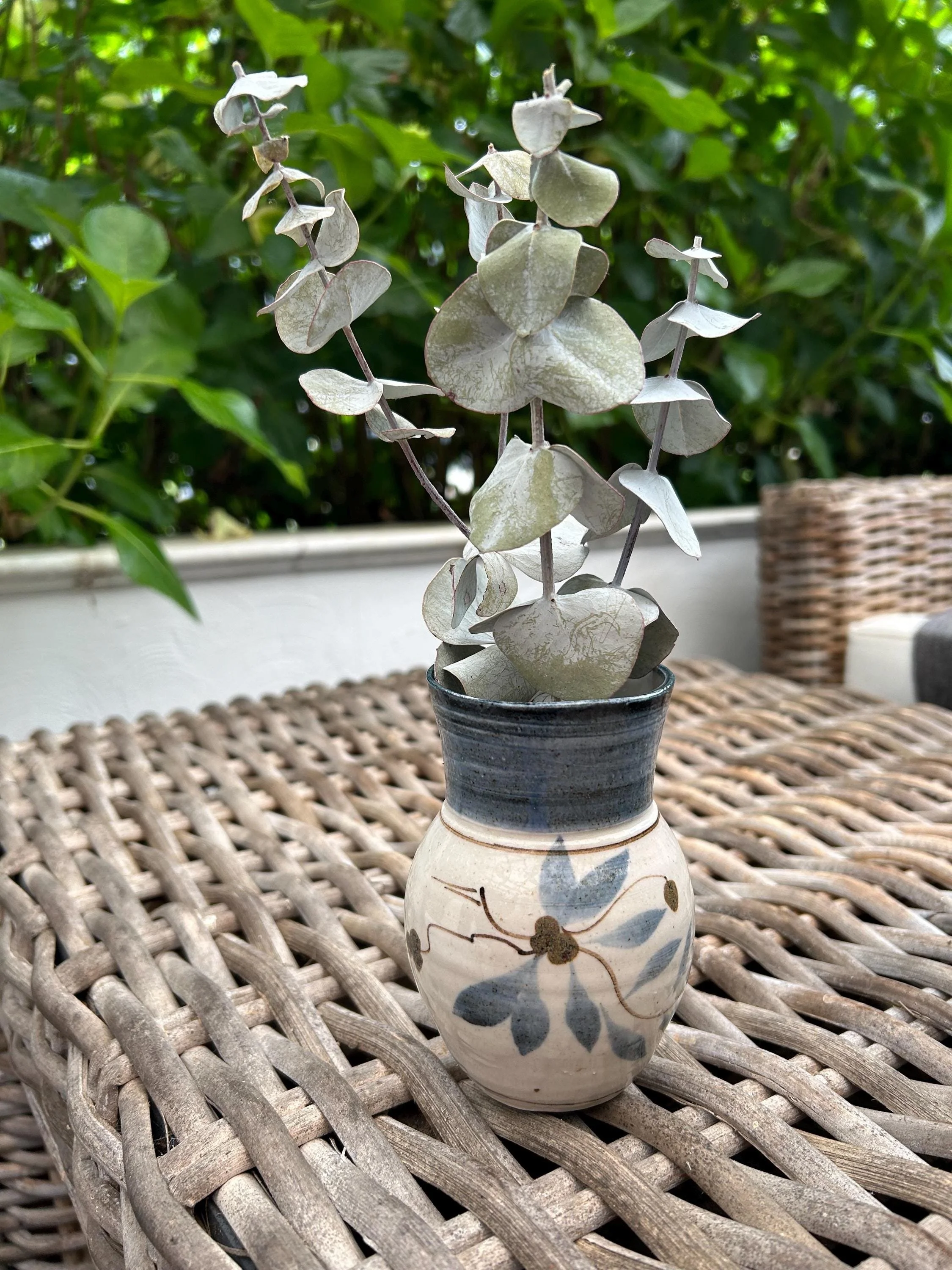 Vase on outdoor table with eucalyptus inside