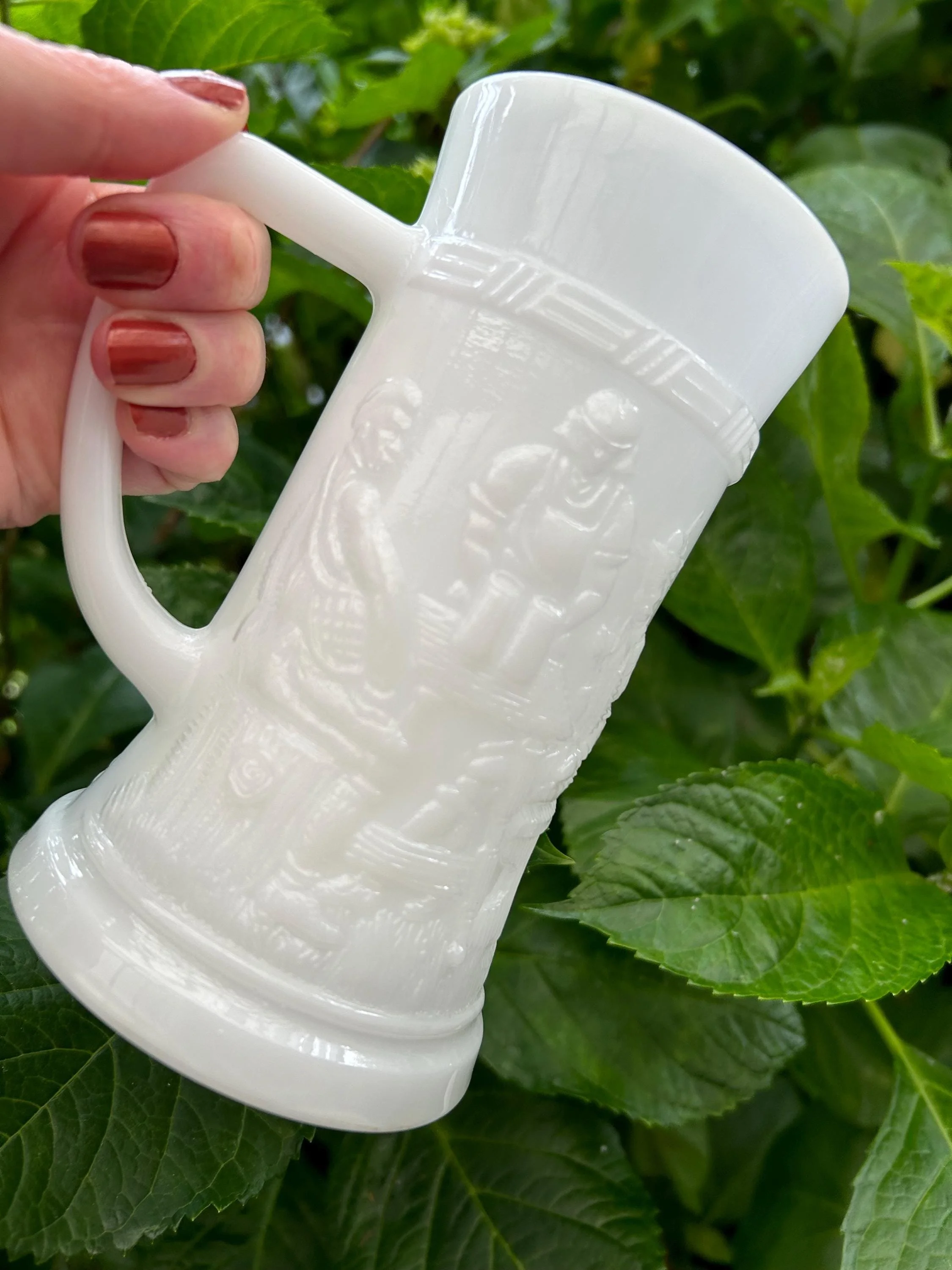 Indiana Glass milk glass stein held in hand – embossed tavern design visible
