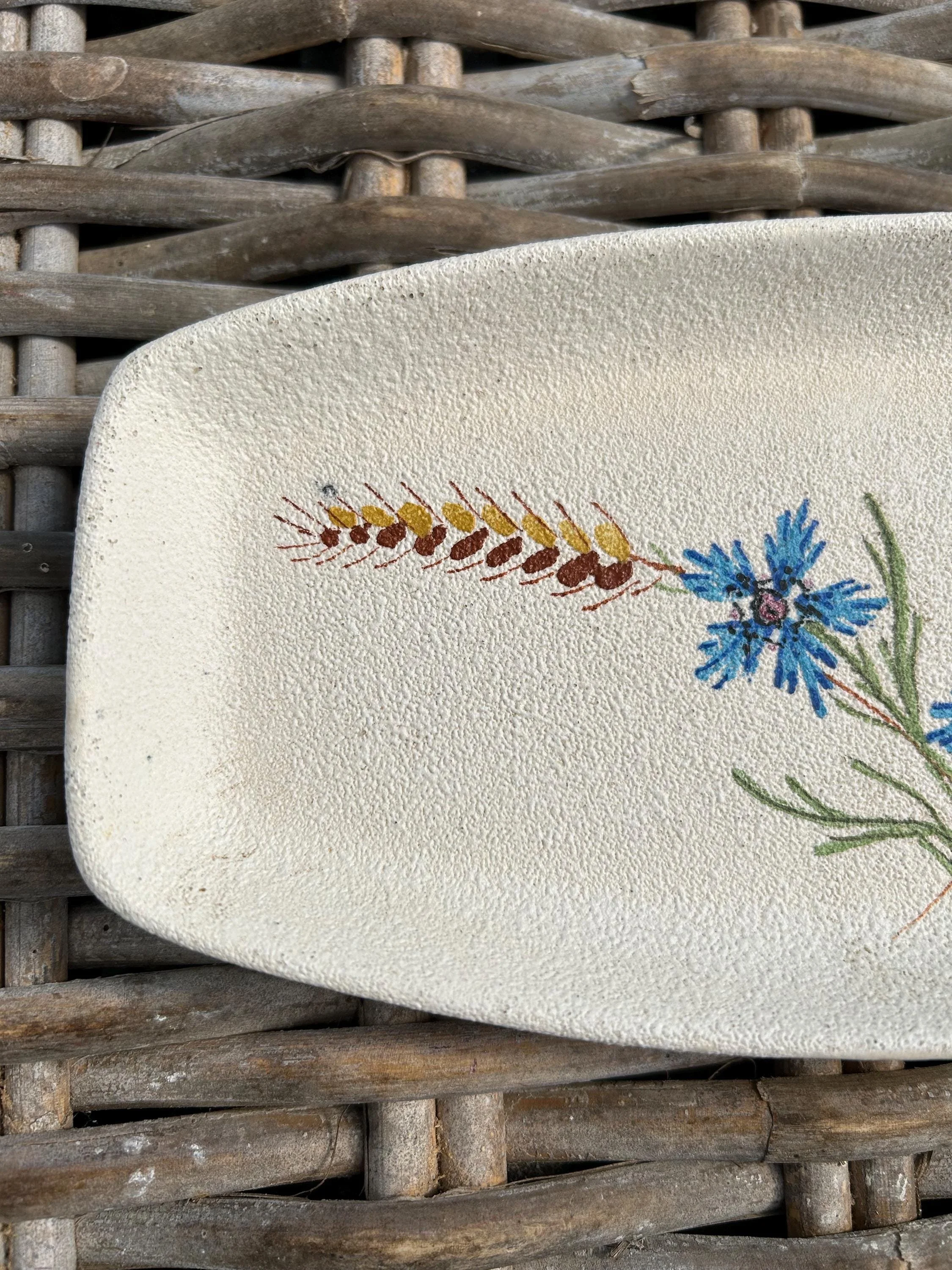 Close-up of tray’s floral and wheat design on textured ceramic surface