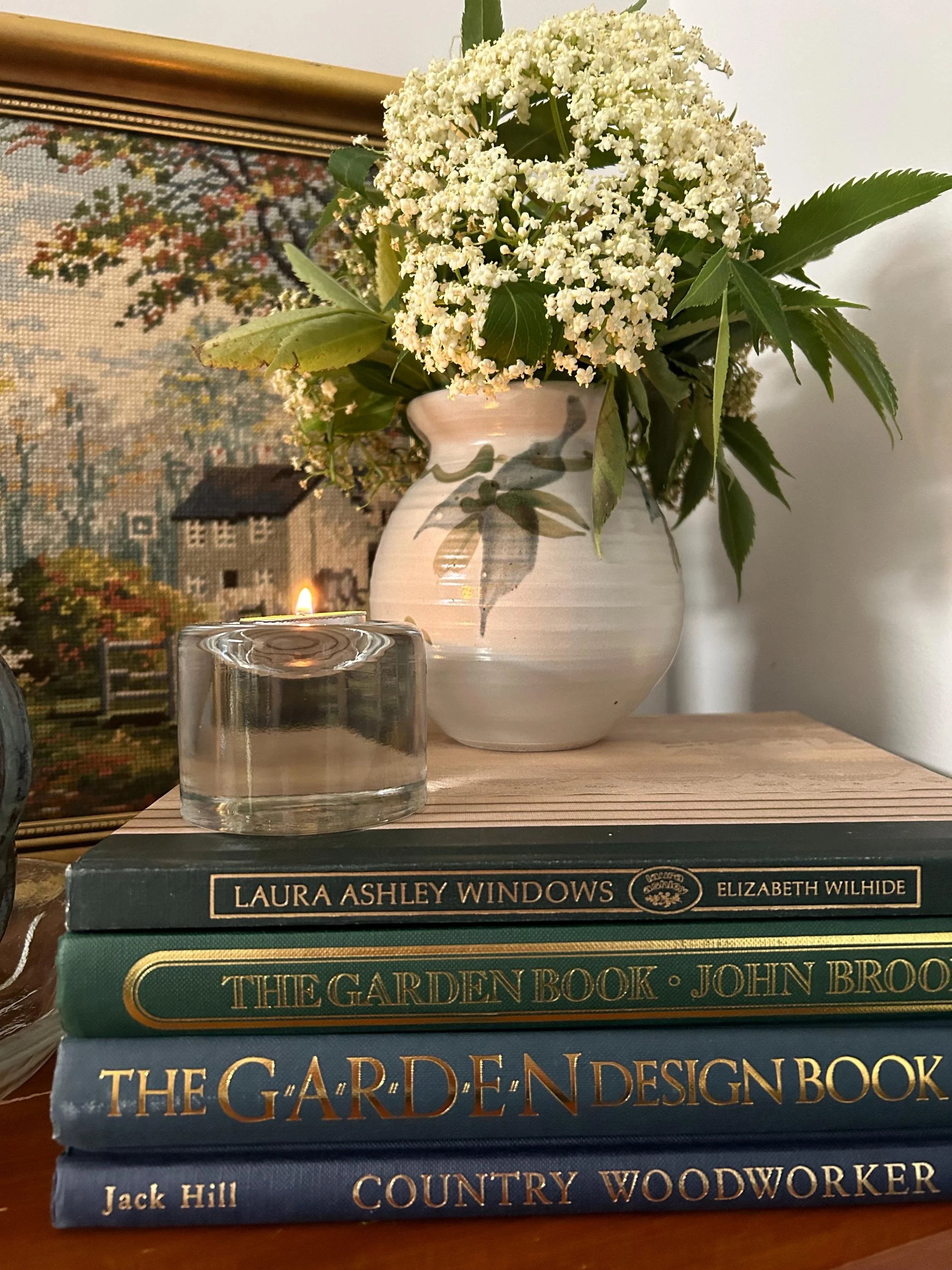 The glass tea light holder displayed on stacked books with a candle lit inside