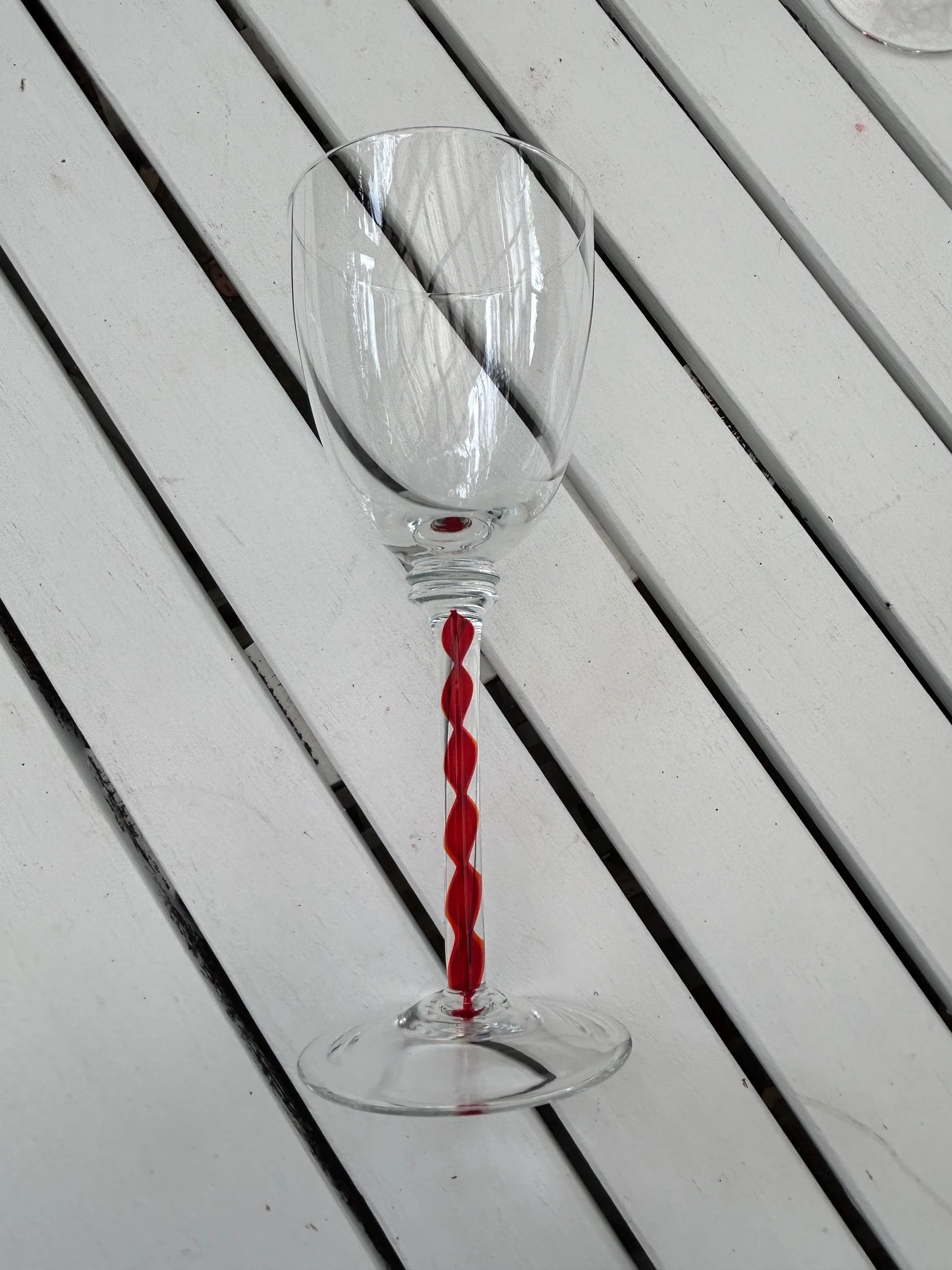 Single upright glass showing clear bowl and bold red stem