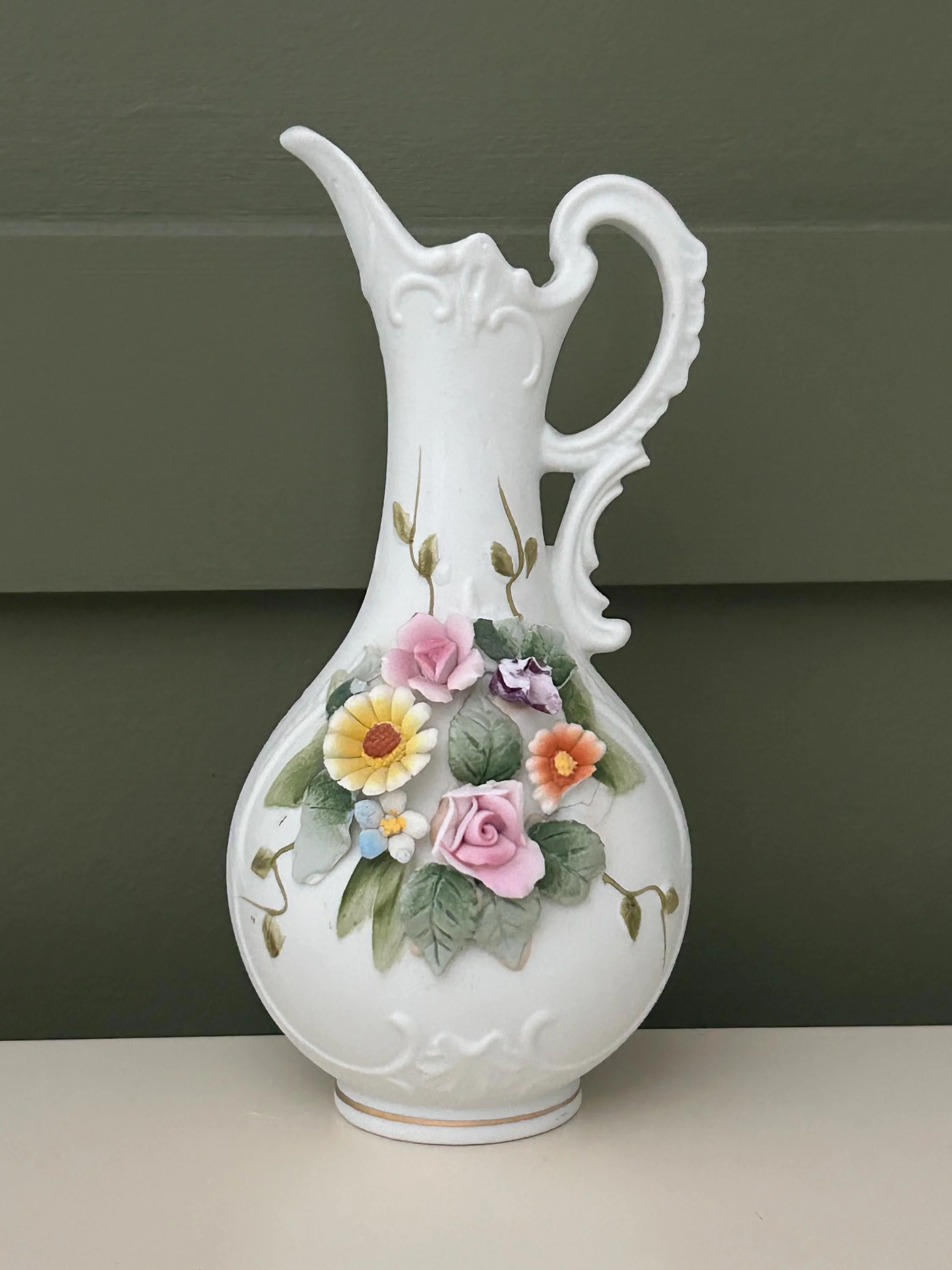 Side view of ornate jug with embossed florals and curved spout