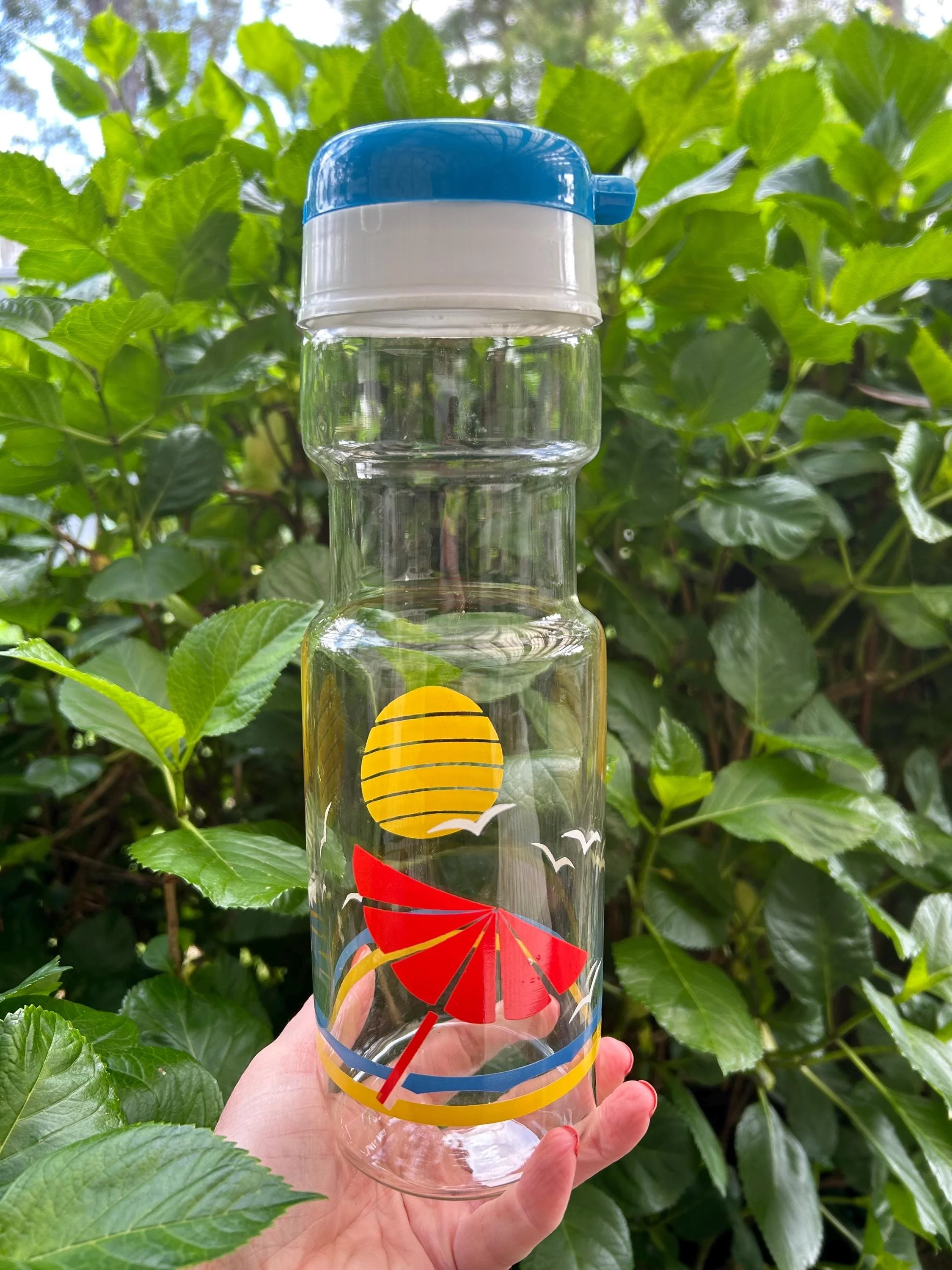 Side view of pitcher showing blue handle lid and sun design