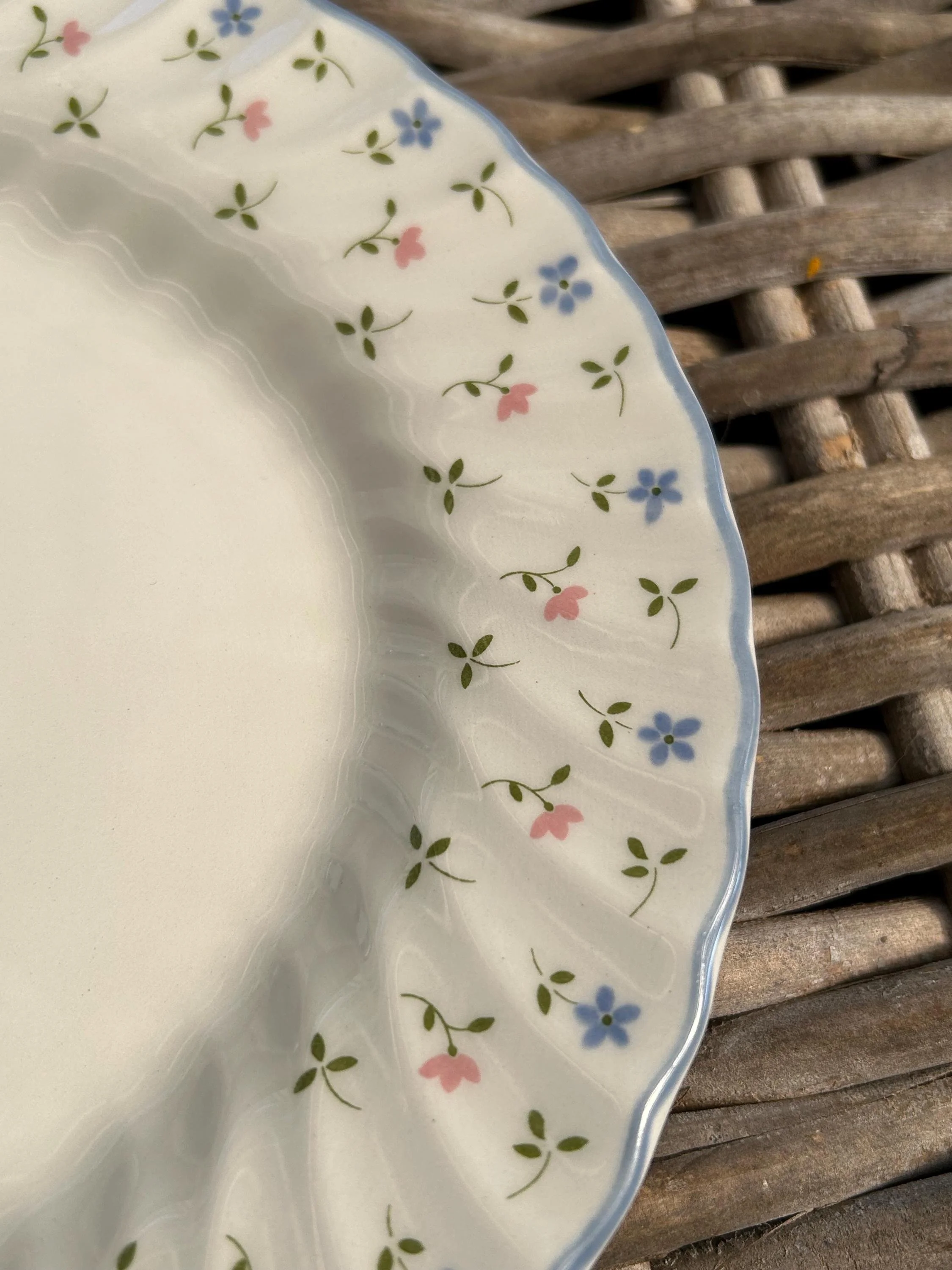 Close-up of rim showing blue and pink flowers with green leaves