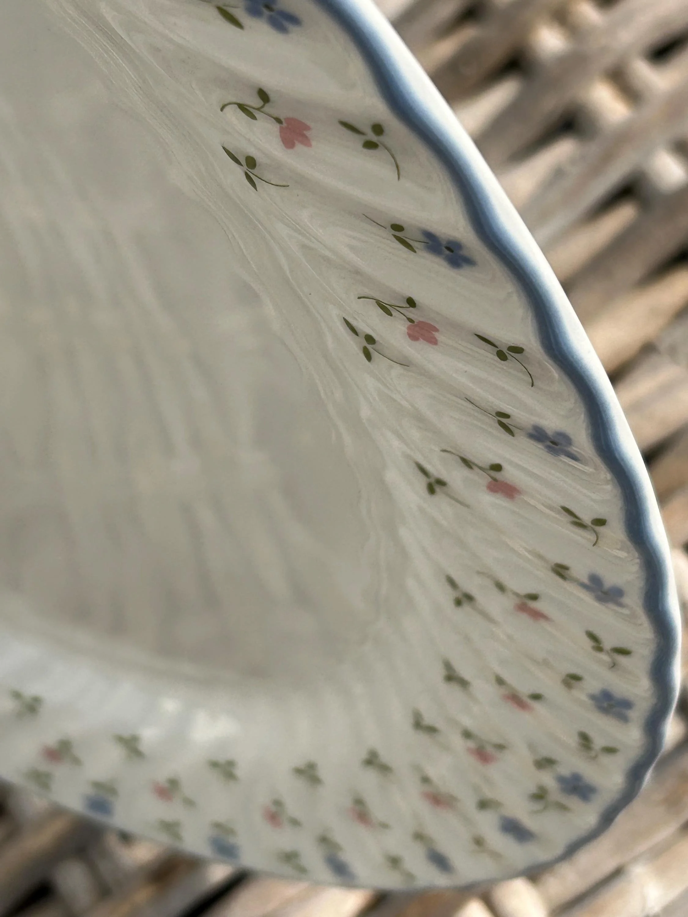 Detail of scalloped rim showing blue edge and pastel floral design