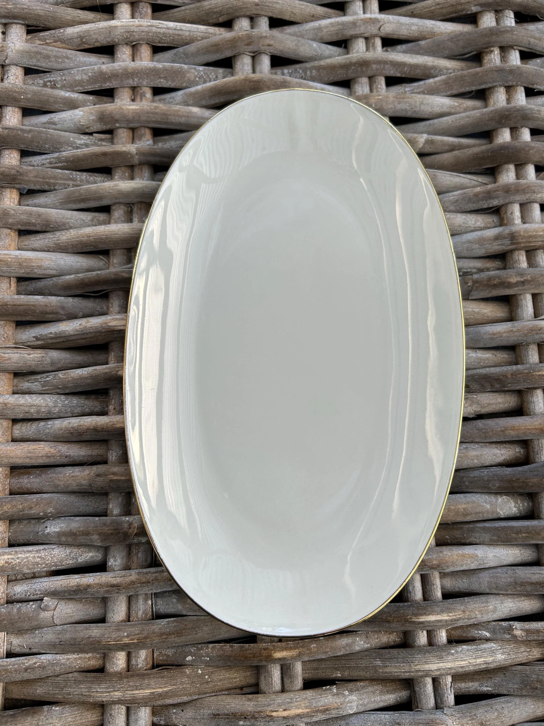 Single oval plate held outdoors showing glossy glaze