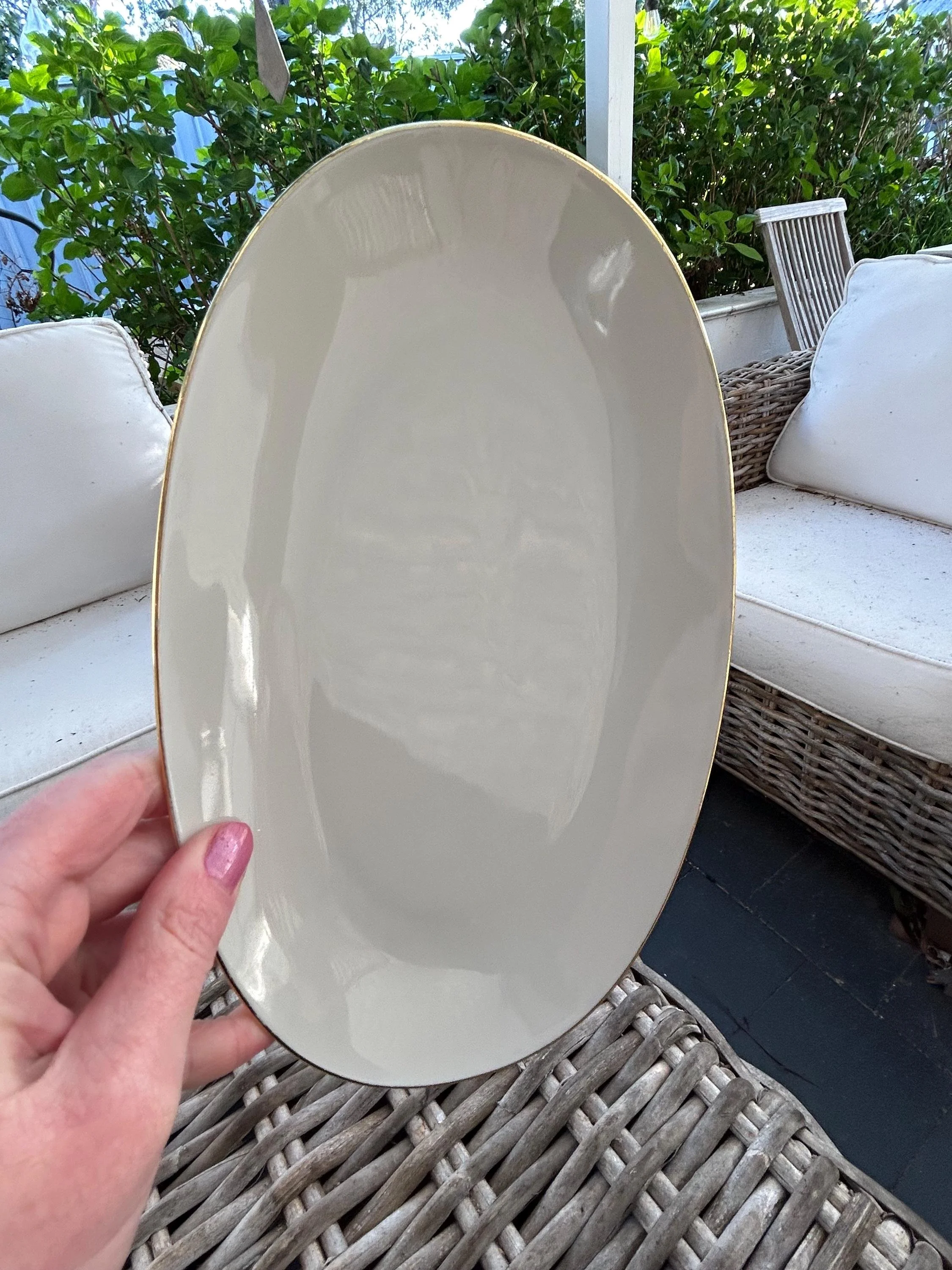 Single oval plate held outdoors showing glossy glaze.
