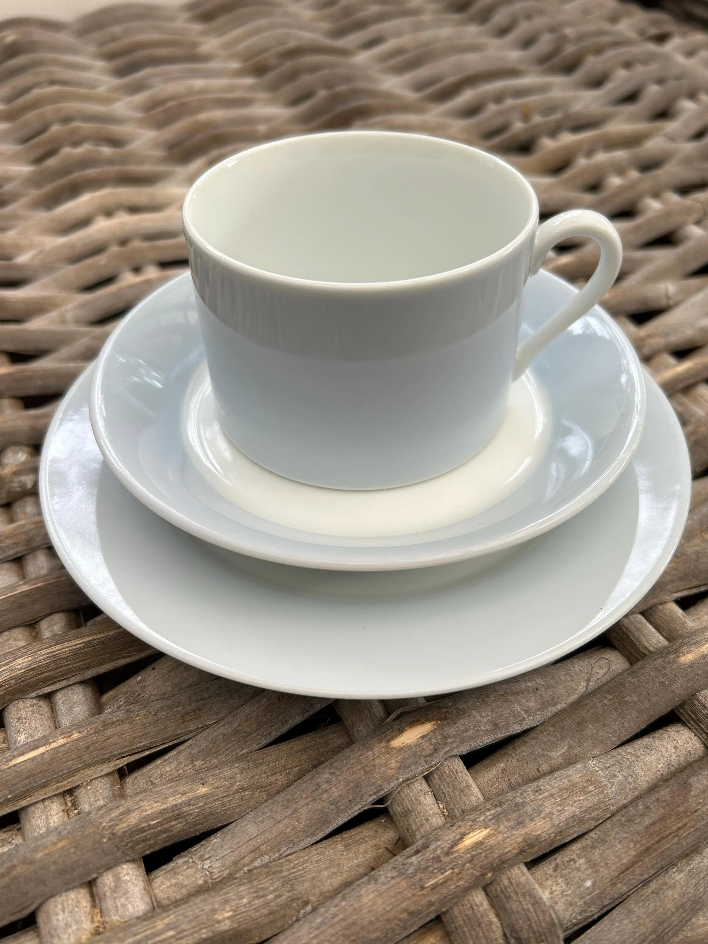 Set of one cup, one saucer, one plate on wicker background