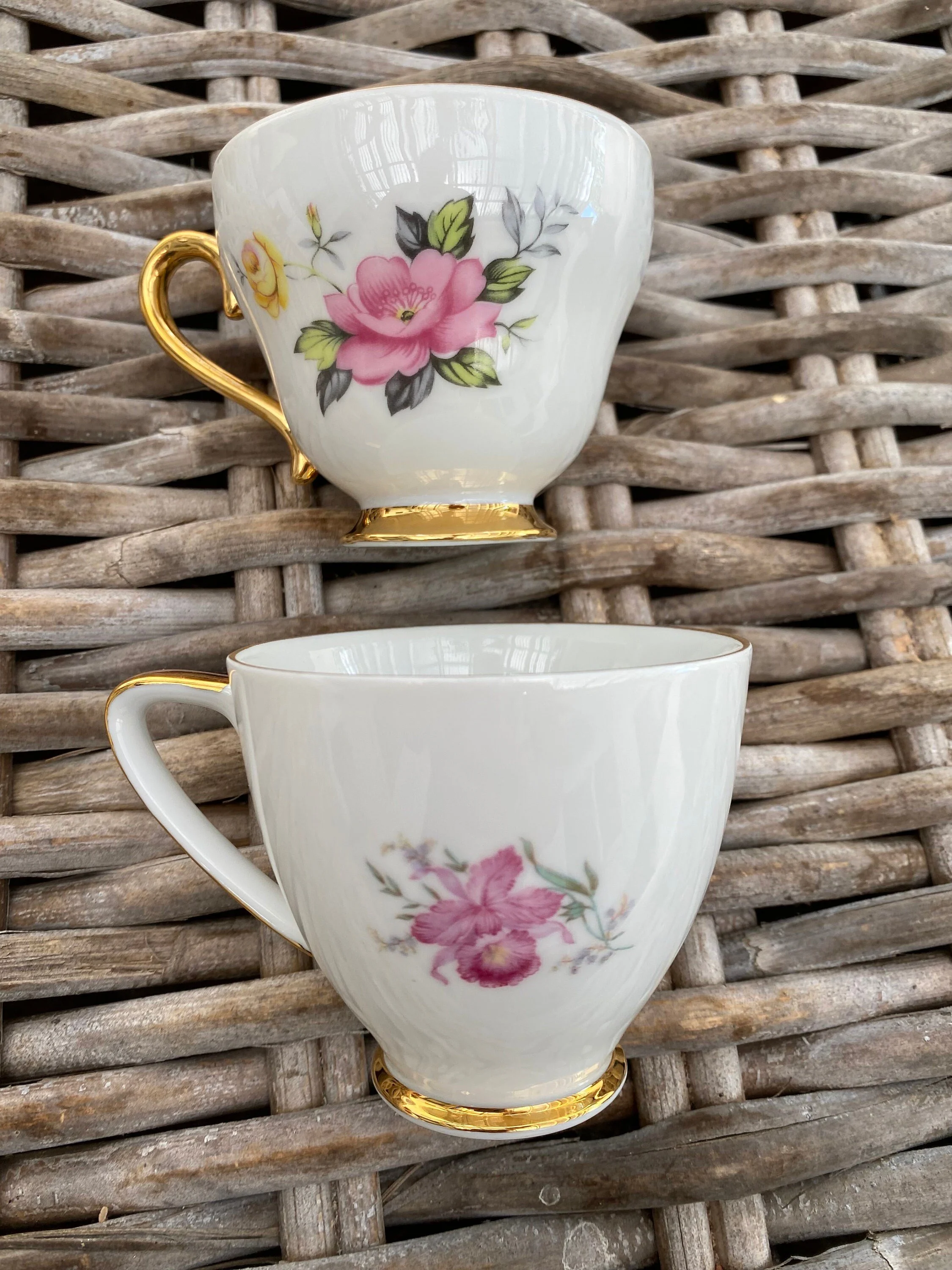 Comparison of the two teacups showing their different floral patterns and matching gold handles