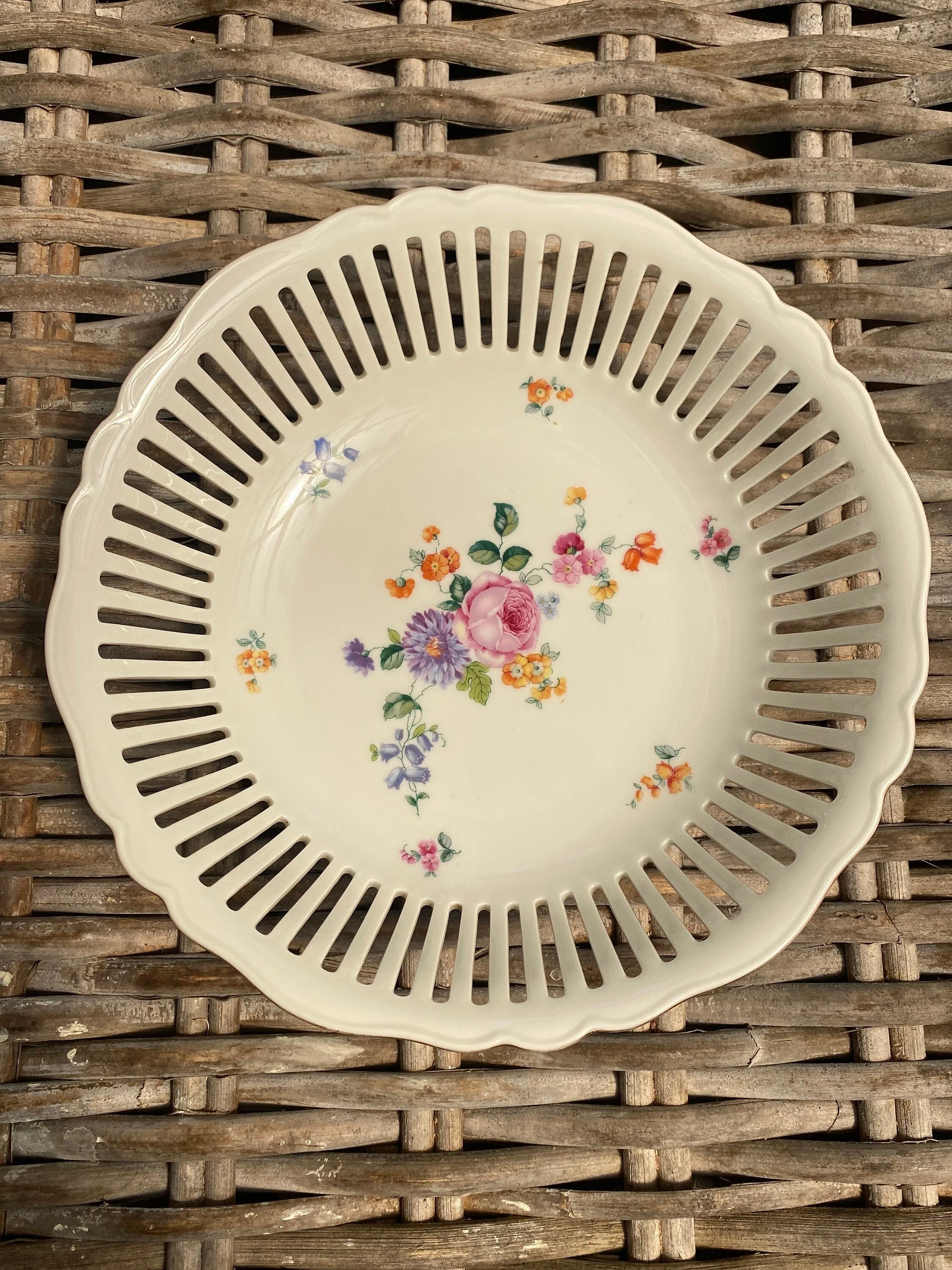 A rare 1922 Czech porcelain bowl with intricate reticulated design, gold trim, and vibrant floral motifs. A true Bohemian vintage treasure.