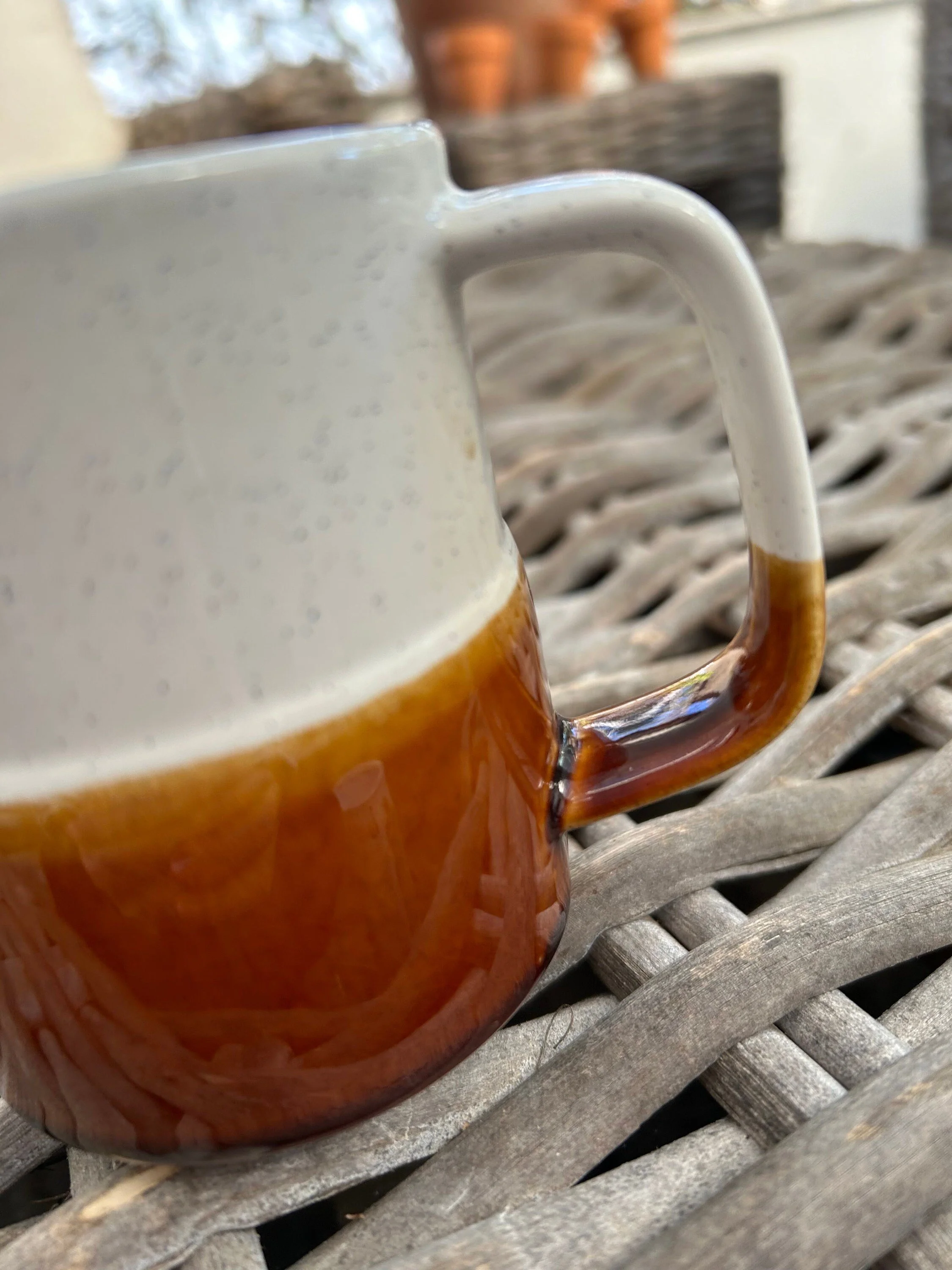 Three-quarter view of the vintage Japanese creamer highlighting the handle shape and speckled finish