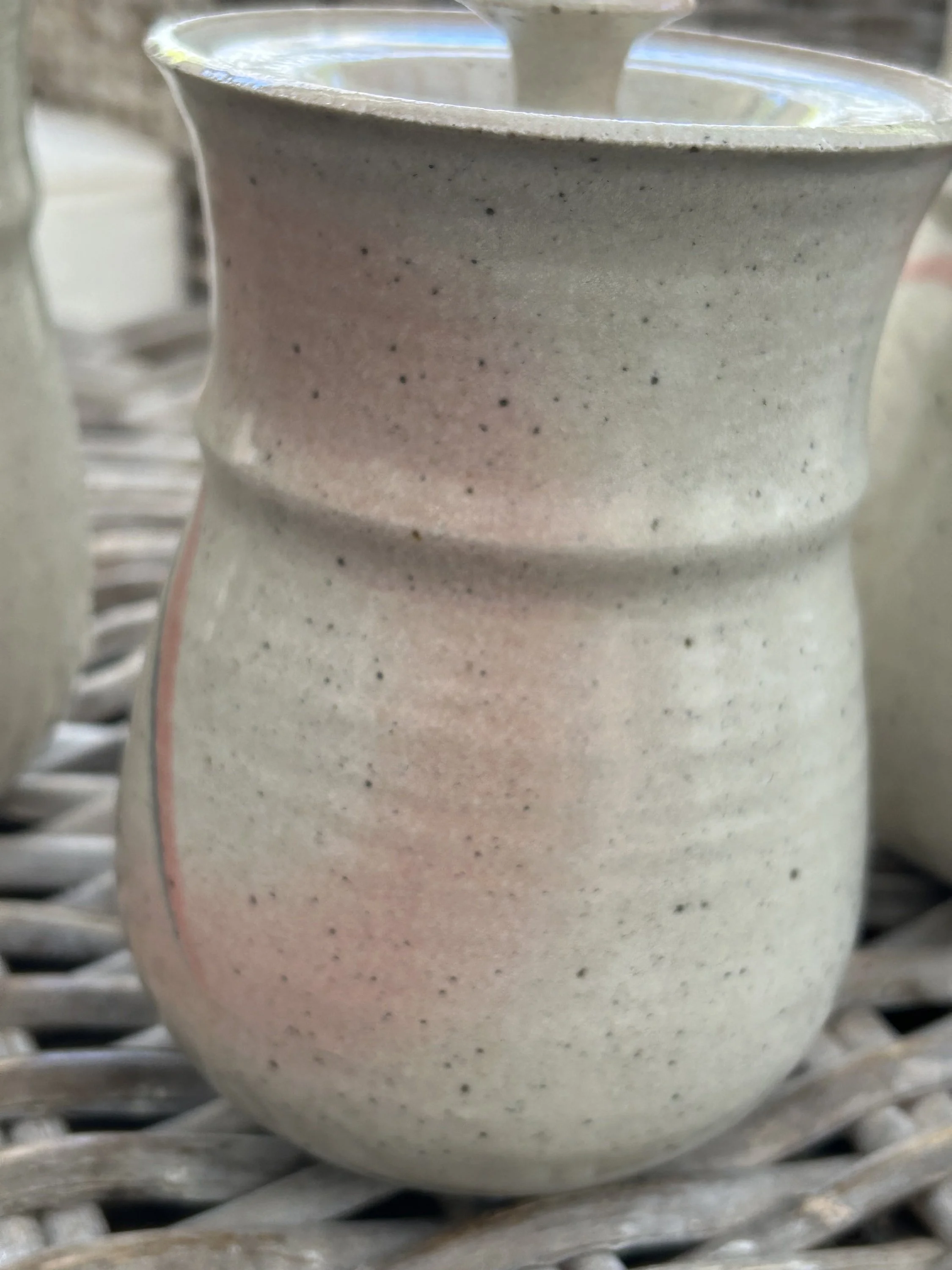 Detail shot of soft pink glaze on the back curve of one canister
