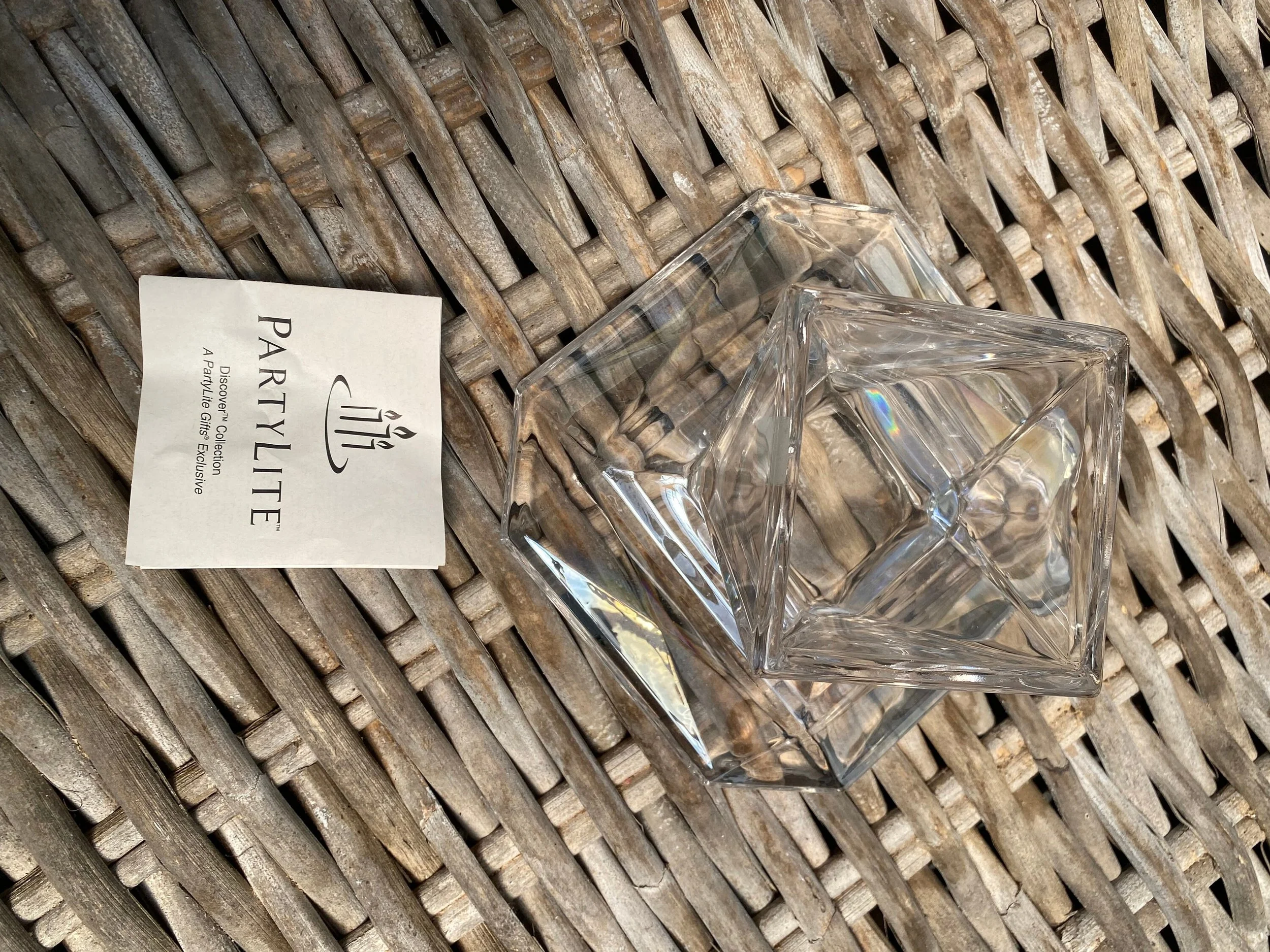 PartyLite candle holder next to branded info card on wicker surface