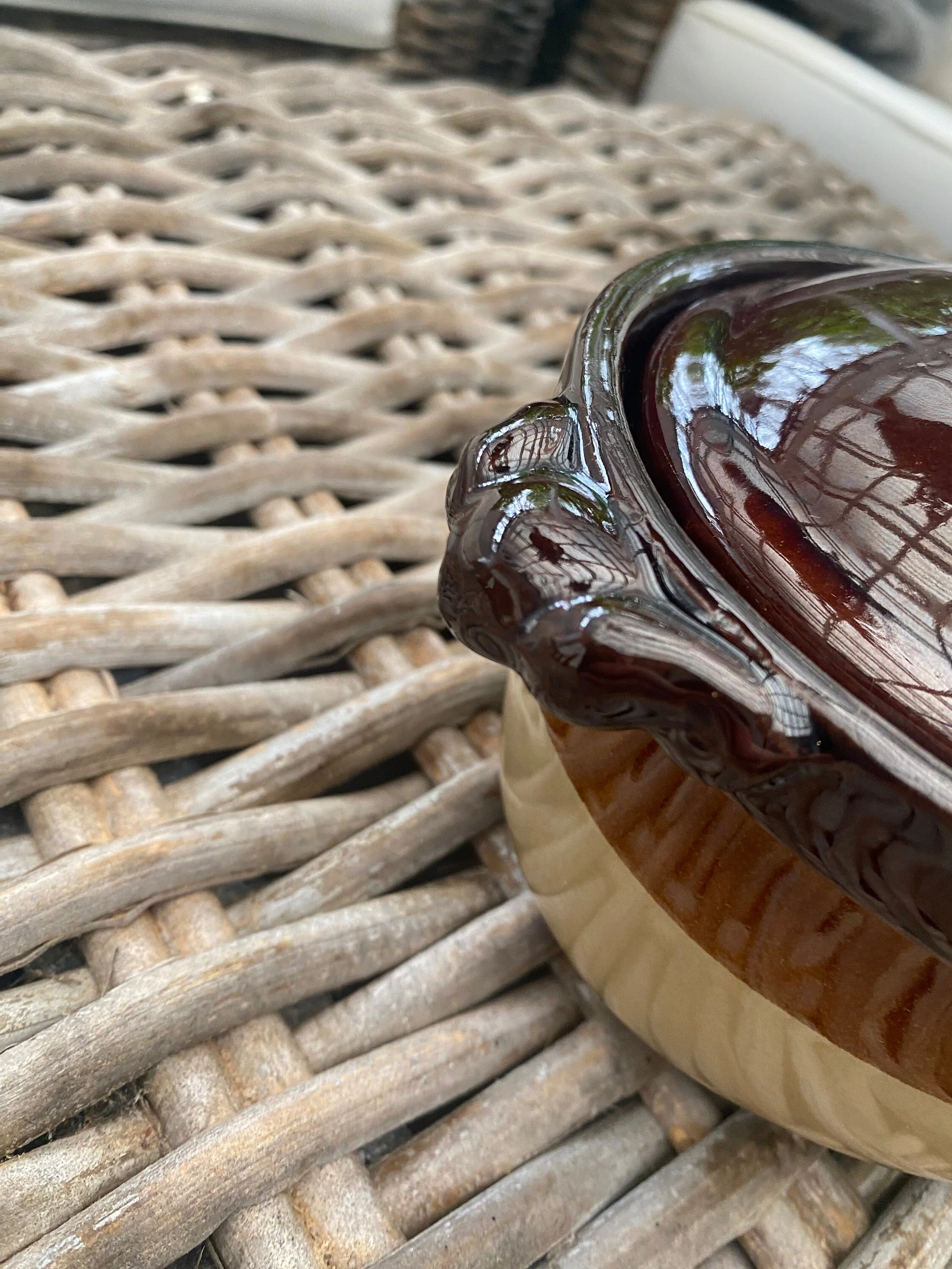 Angled close-up of one decorative side handle and lid edge detail