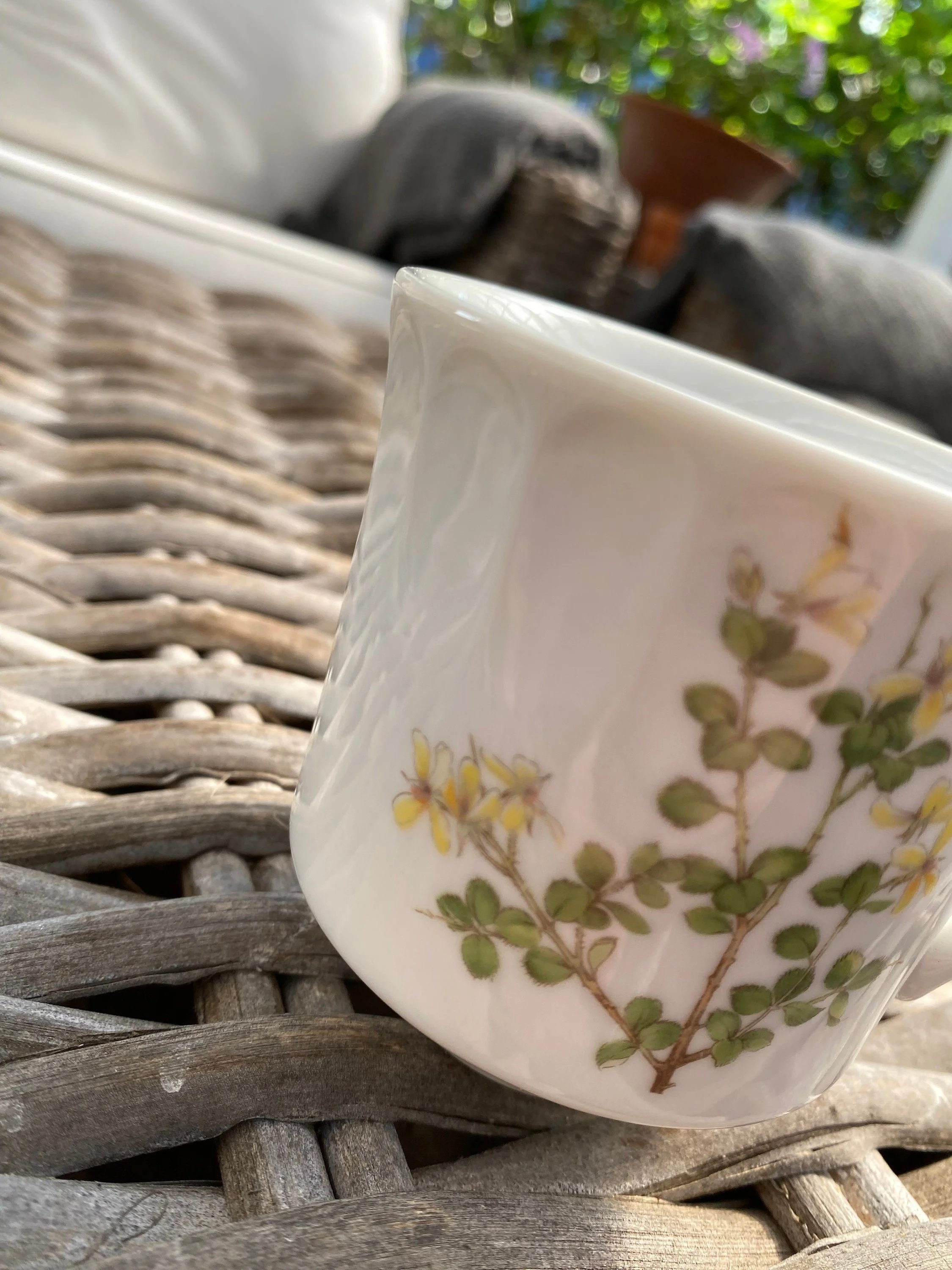 Close-up of floral motif on white ribbed cup showing yellow flowers and green foliage