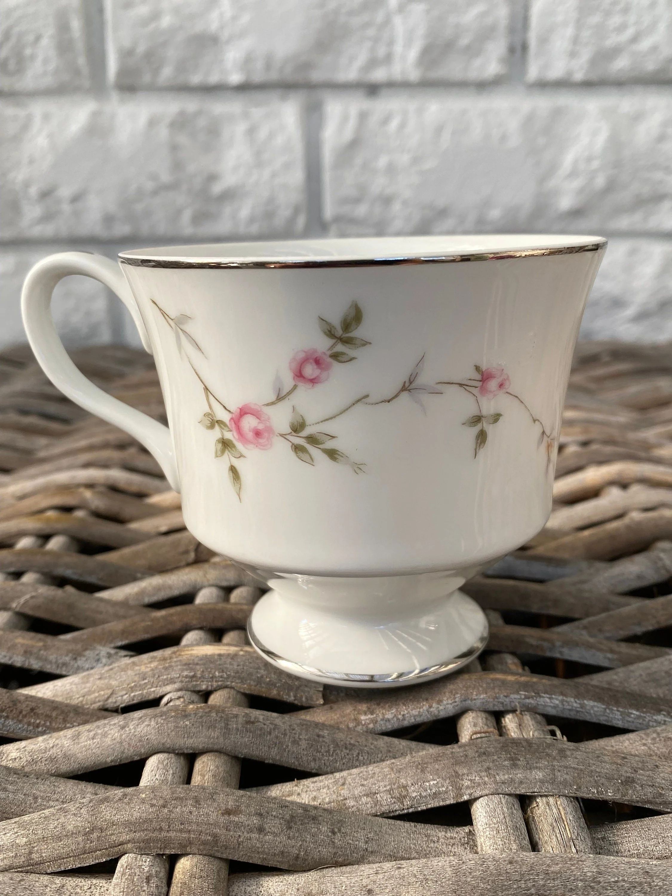 Three Crown teacup showing floral pattern and gold trim on wicker table