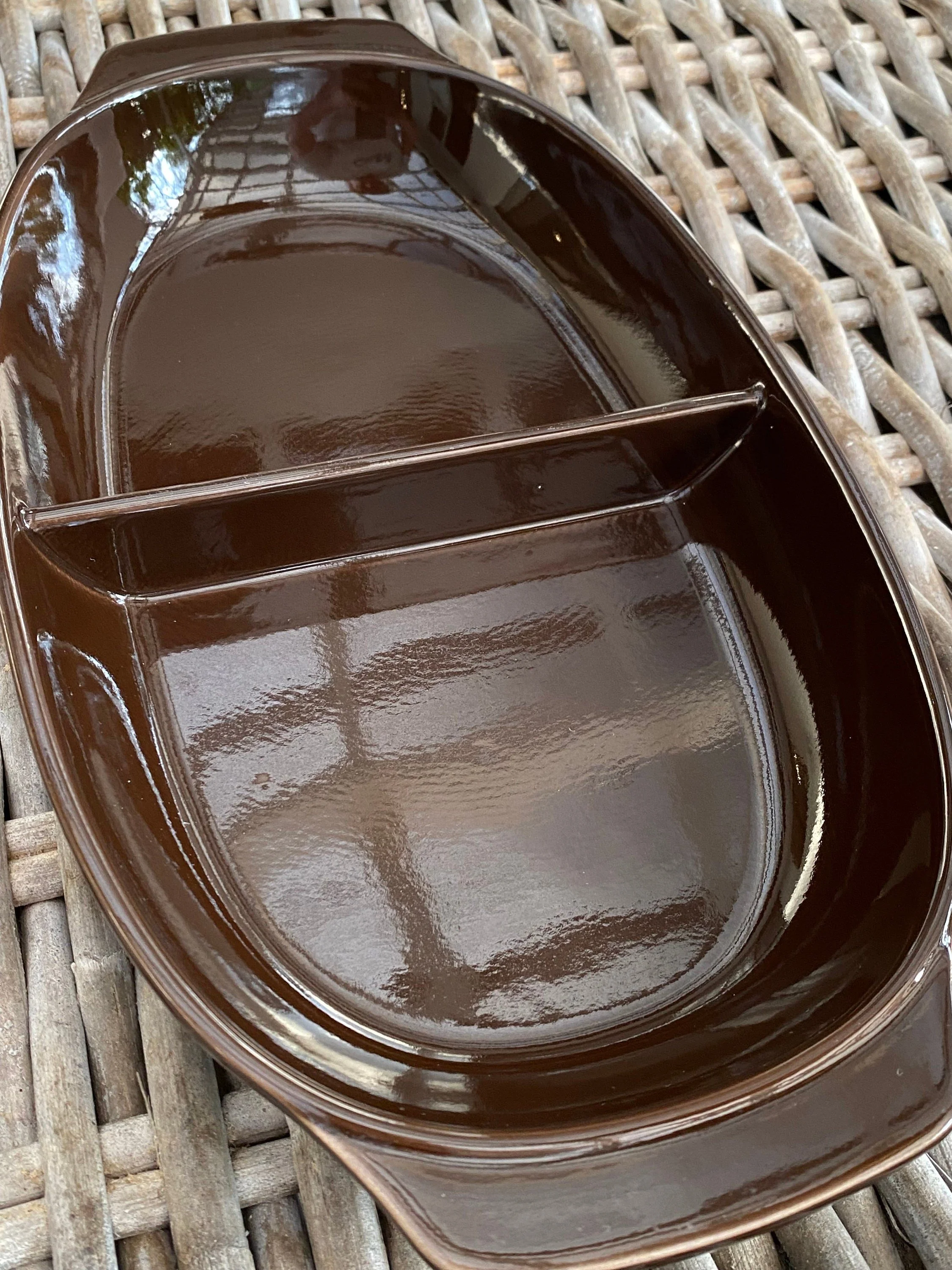 Overhead view of divided brown serving dish showing glossy glaze and compartments