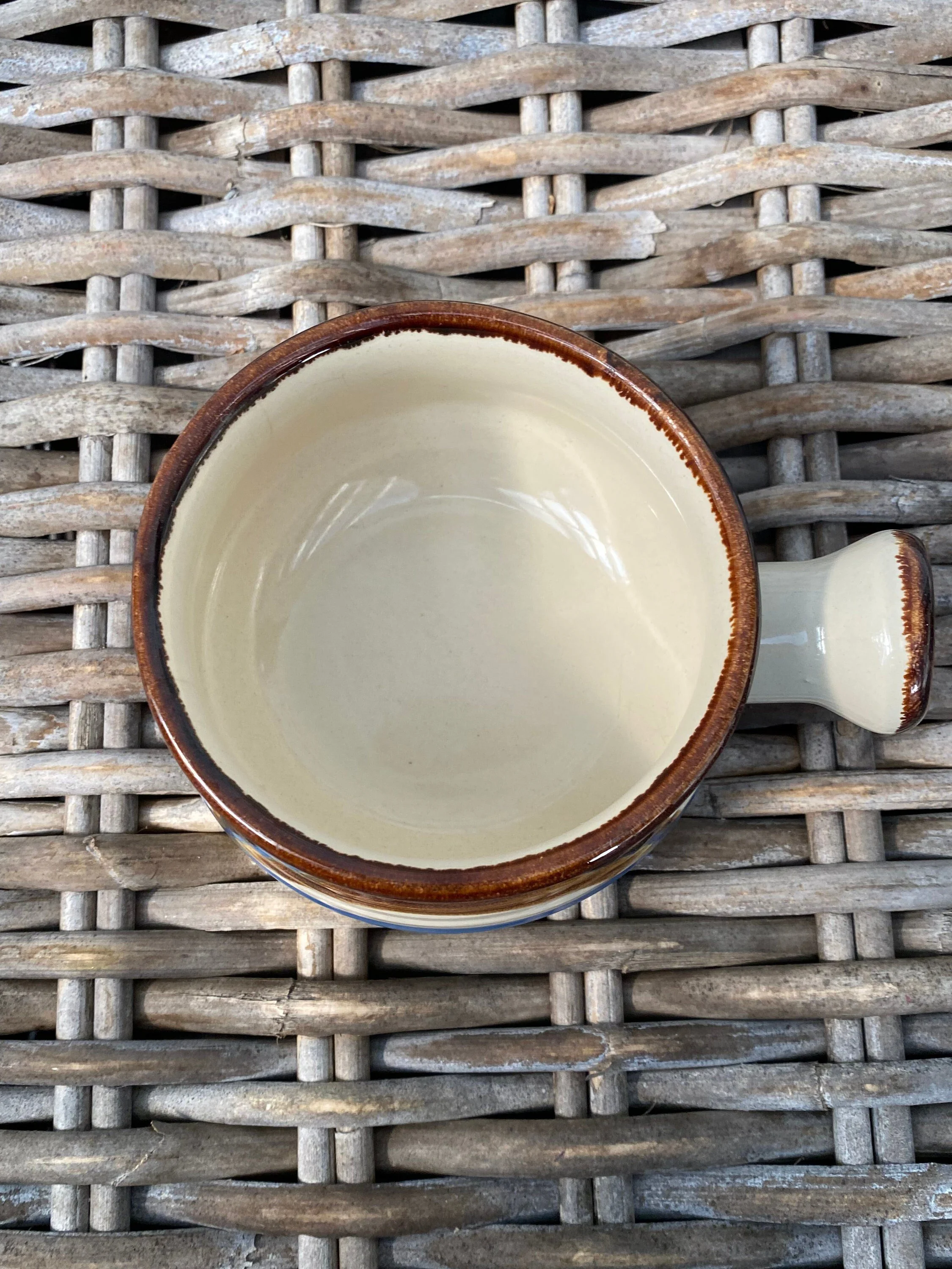 Top view of vintage stoneware bowl showing interior depth, brown rim, and side handle