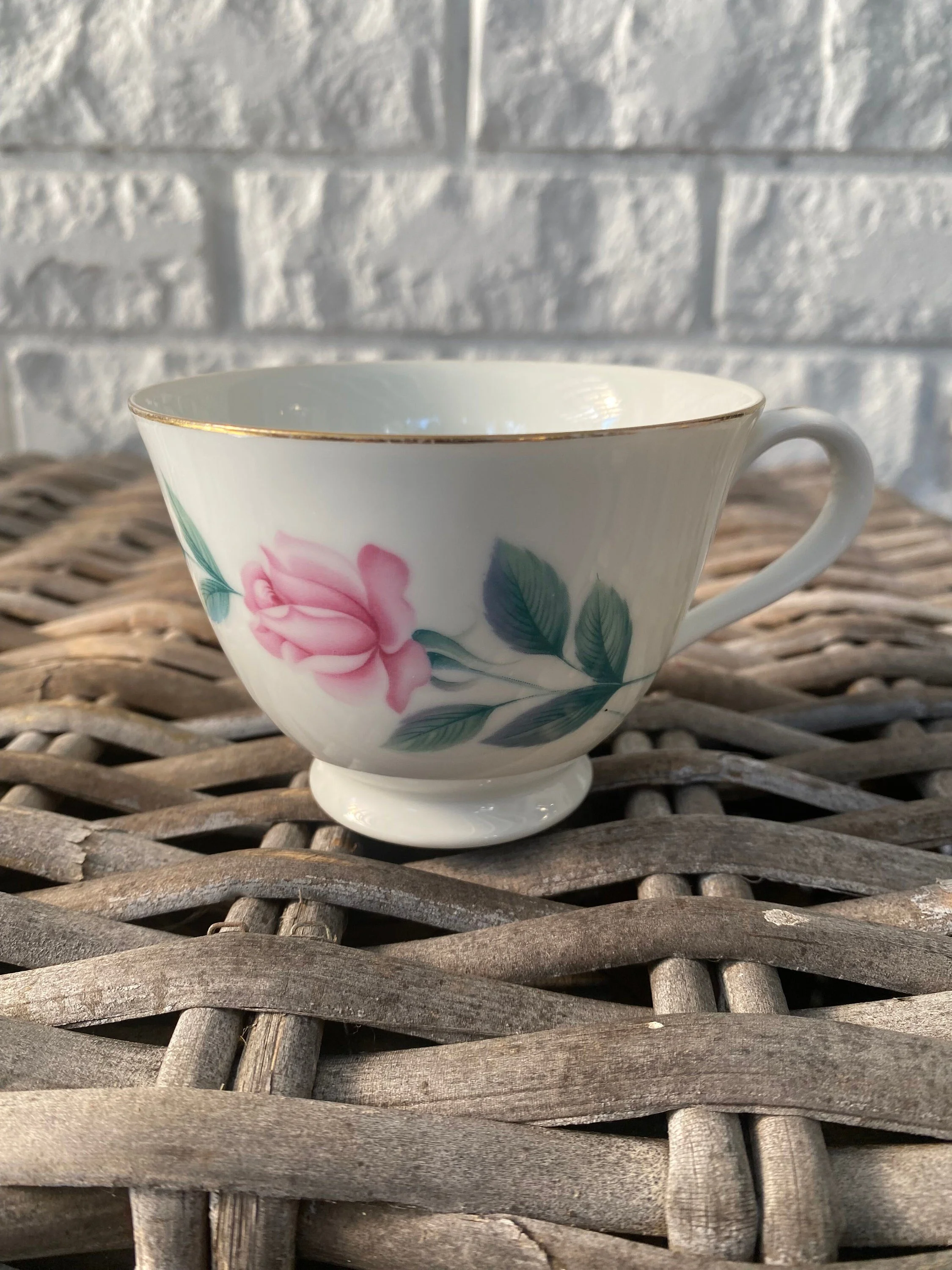 Close-up of gold-rimmed teacup with full pink rose motif