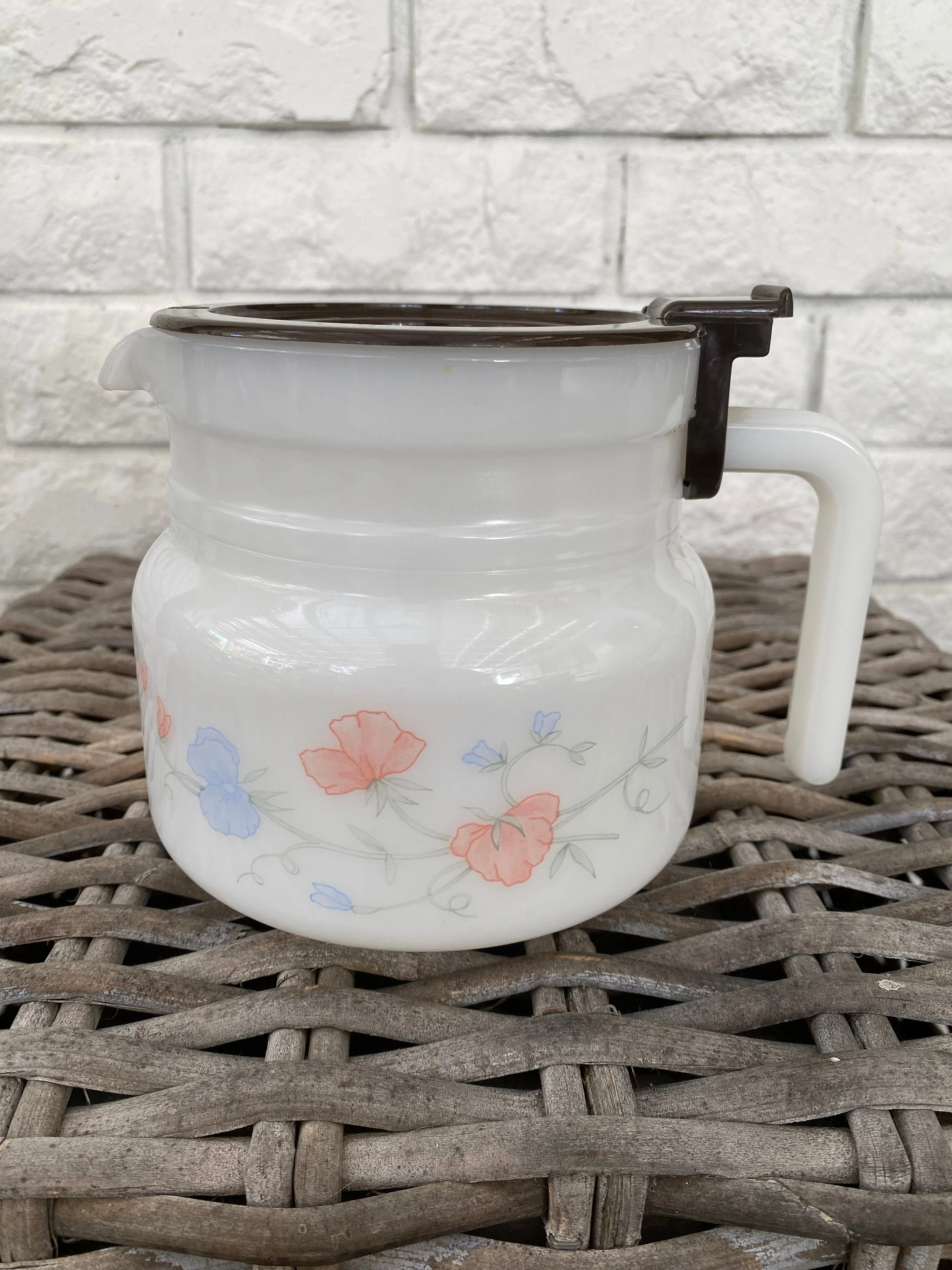 A vintage 1980s Arcopal coffee pot with a sweet pea floral design. Heat-tempered milk glass, removable brown lid, and a versatile pitcher function.