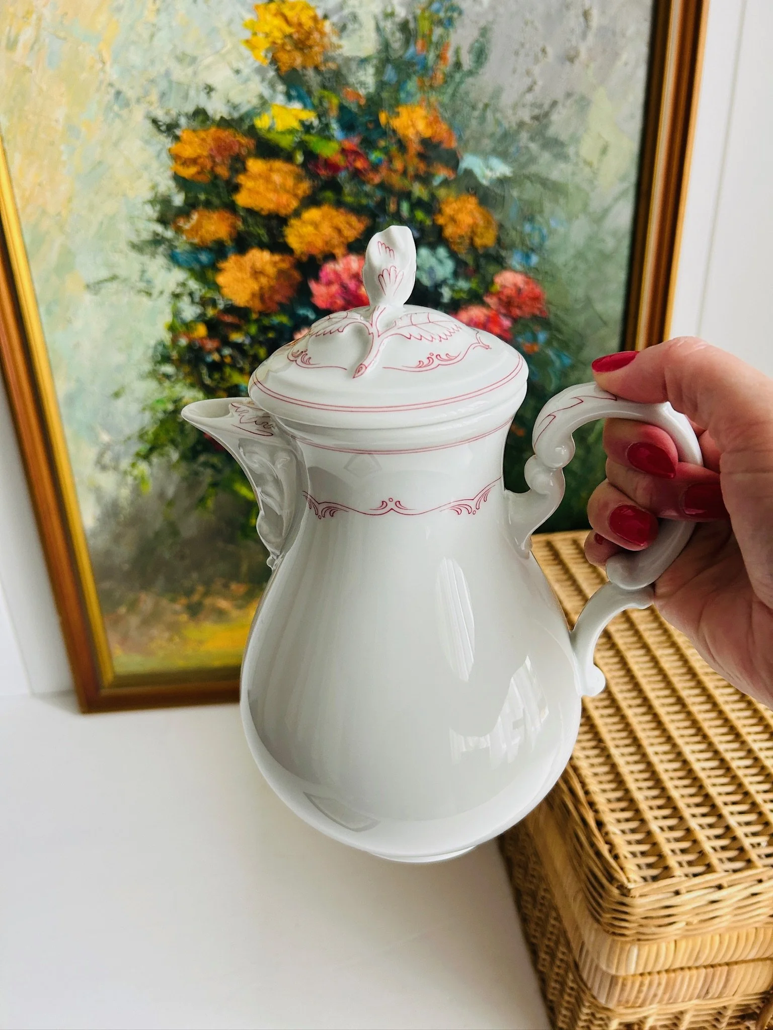 Full view of the coffee pot held by the handle, showing the tall bulbous shape, pointed spout, and decorative lid.