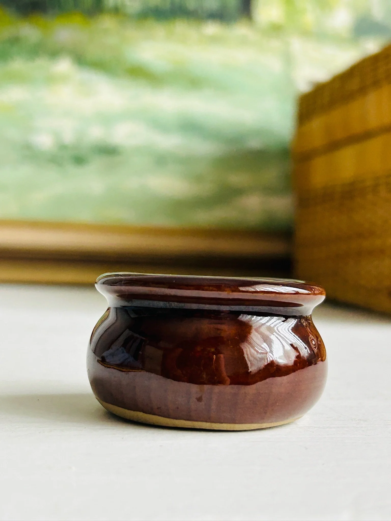 Side view of the Moira salt cellar on a white surface with its rounded body and dark brown glaze visible