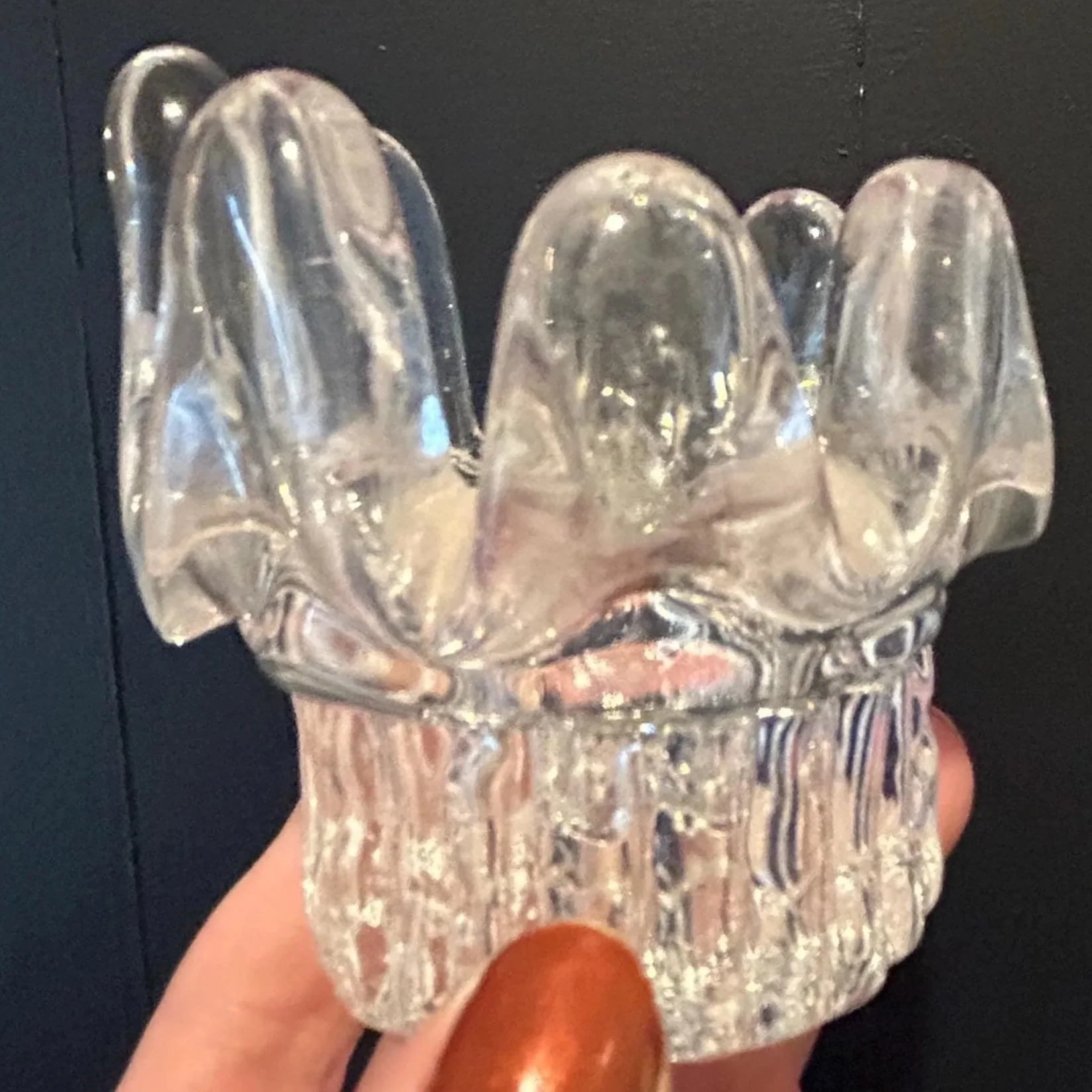 Hand holding candle holder to show vertical ridged stem and petal-shaped rim