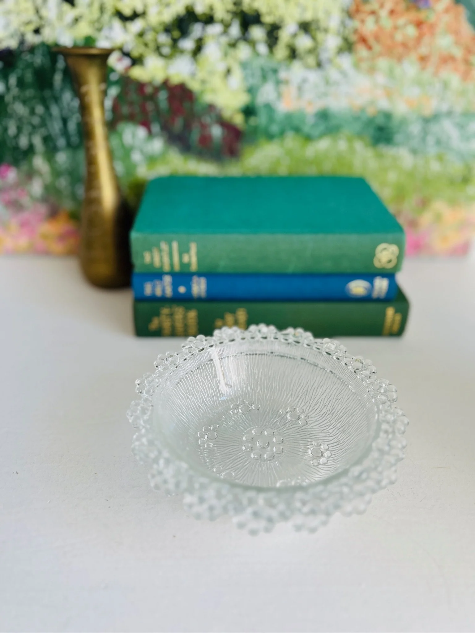 Full view of one bowl on a tabletop with stacked books in the background, showing its size and sculptural form.