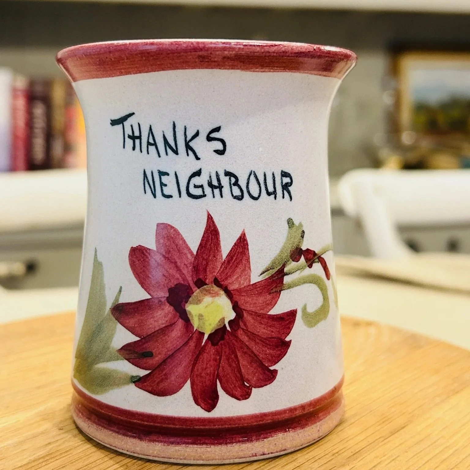 Front view of hand-painted ceramic vase with “Thanks Neighbour” text and burgundy floral design on a light matte glaze