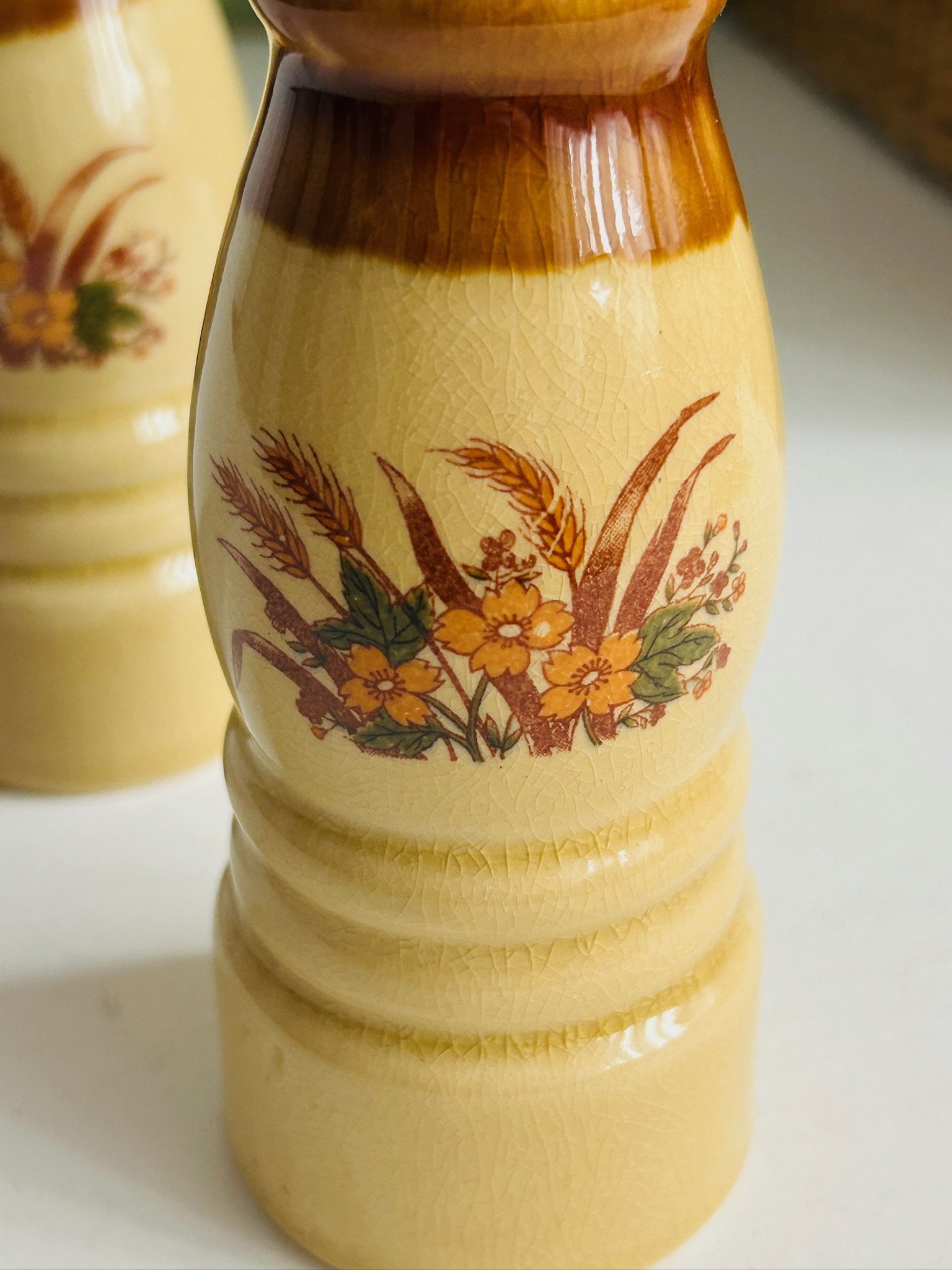 Close-up of the wheat and floral motif on the cream glazed ceramic body