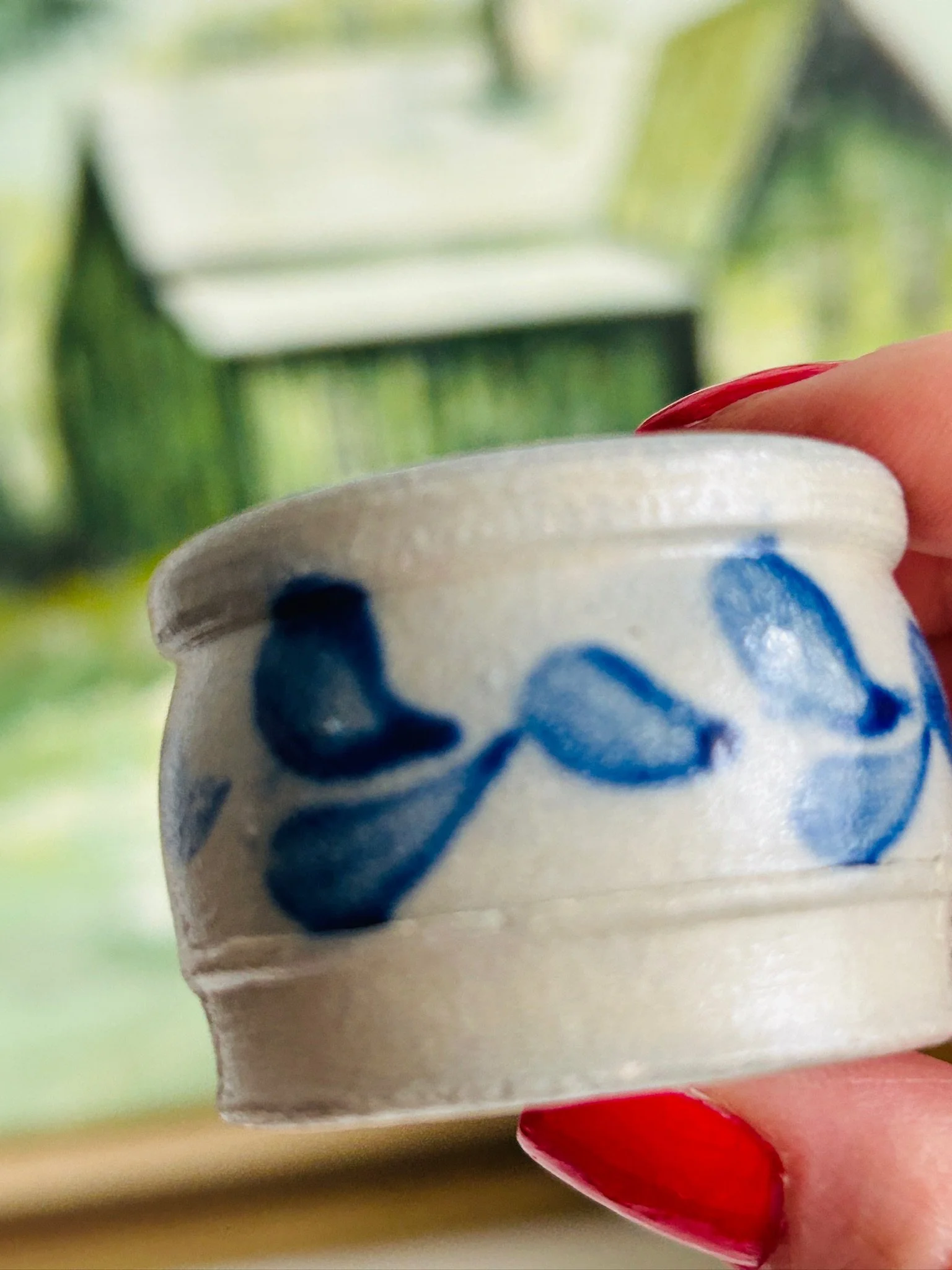 Close-up front view of the handmade stoneware salt cellar with blue leaf motif, showing the rolled rim and painterly decoration