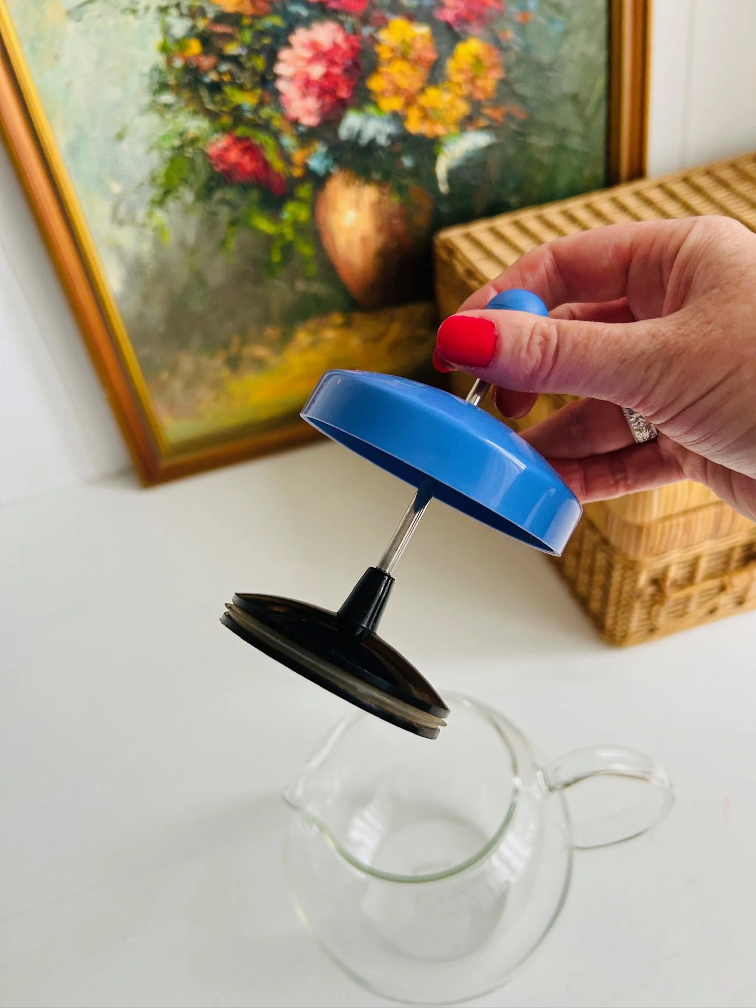 Plunger lid lifted above the teapot, showing the blue lid, metal press rod, and black plunger mechanism.