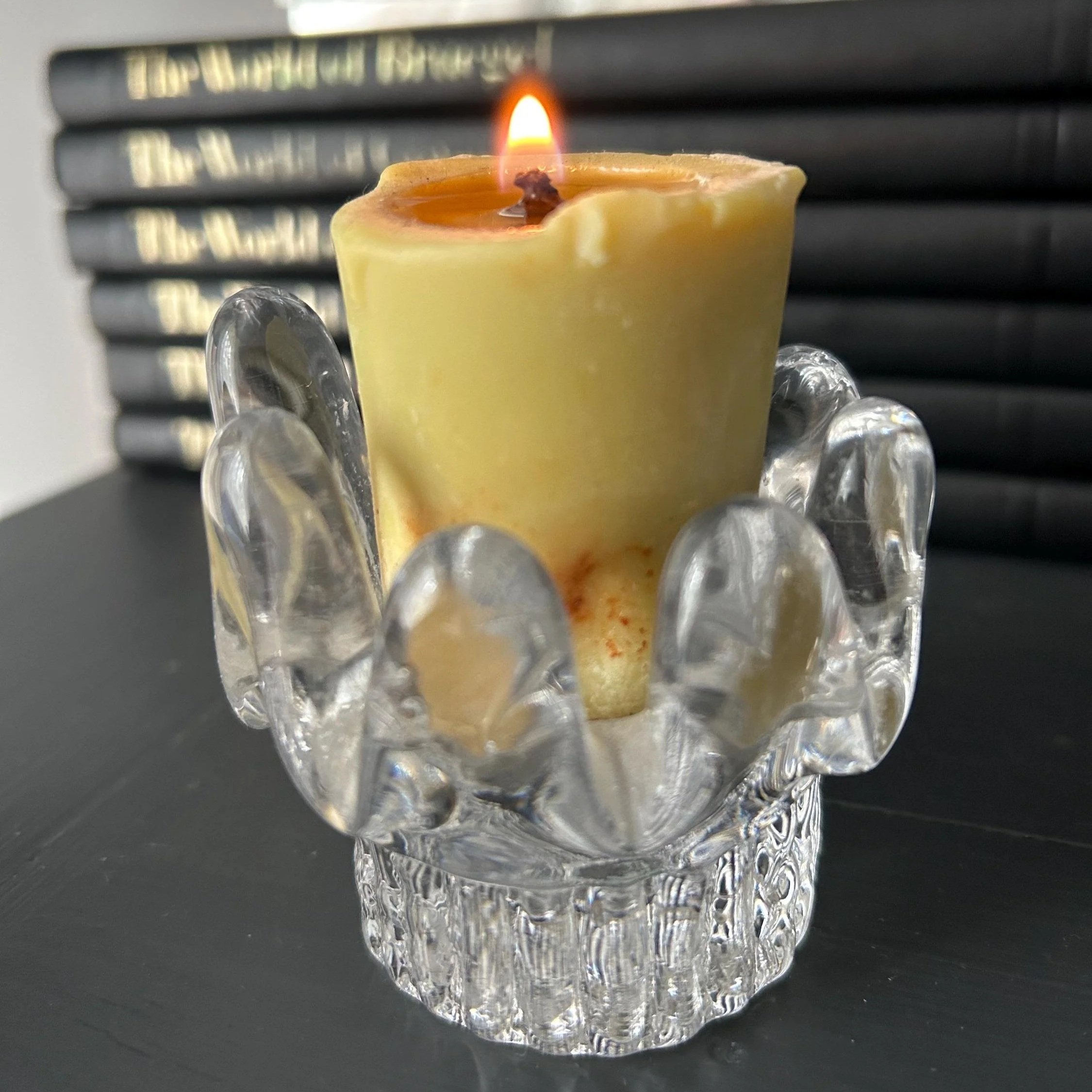 Kosta Boda sunflower candle holder with lit beeswax votive on dark surface