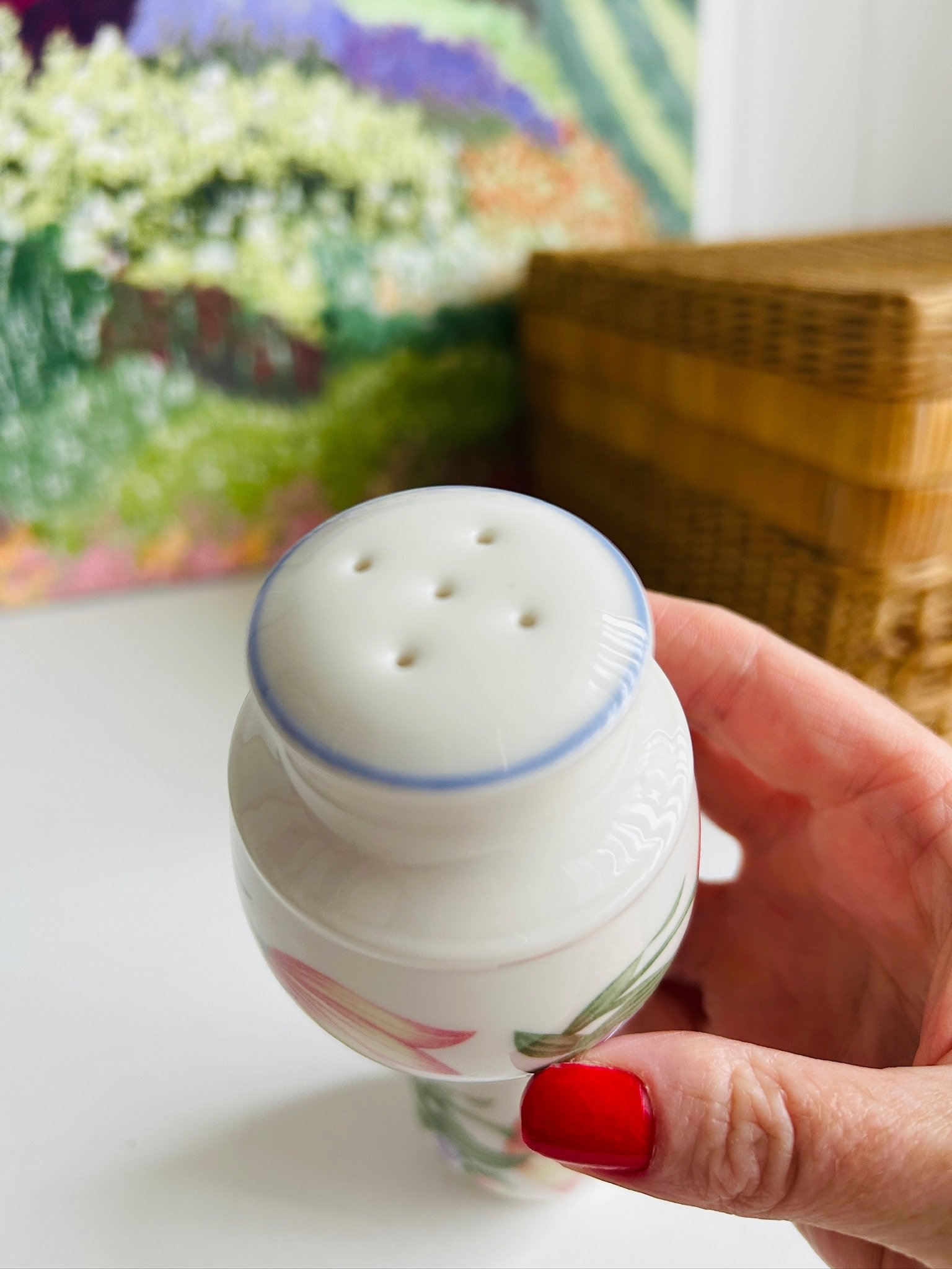 Top view of one shaker held in hand showing the shaker holes and pale blue rim