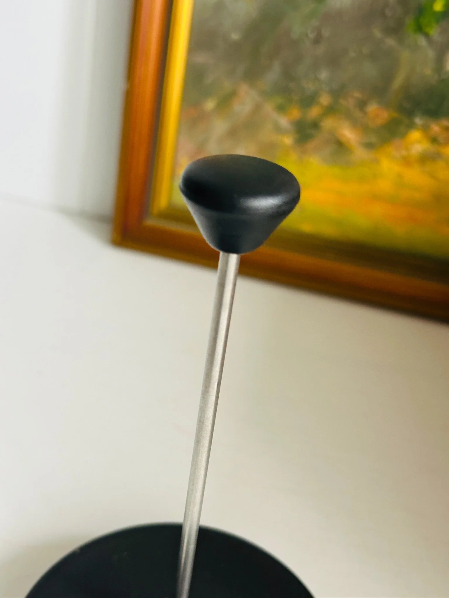 Detail of the curved black handle attached to the frame, highlighting the ergonomic shape and glossy finish.