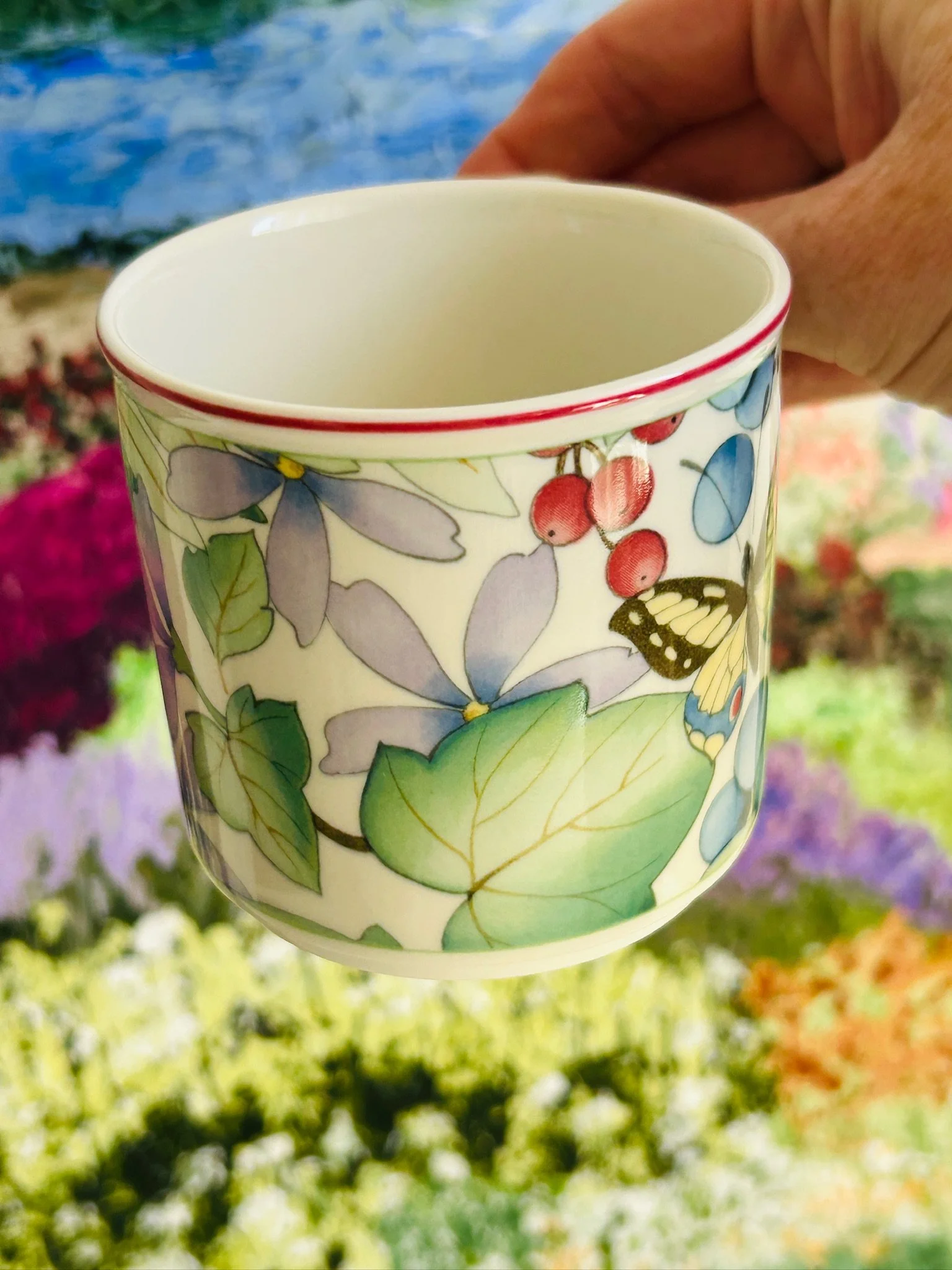 Side view of the coffee cup highlighting the butterfly motif, berries, and leafy botanical design.