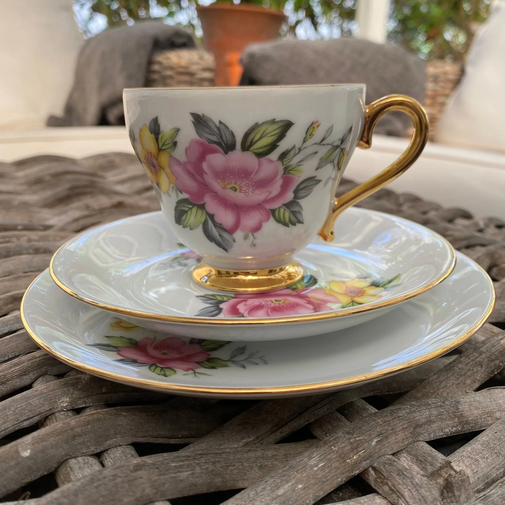 Close-up of one Westminster teacup on its saucer and plate, featuring pink and yellow floral decoration and a gold handle
