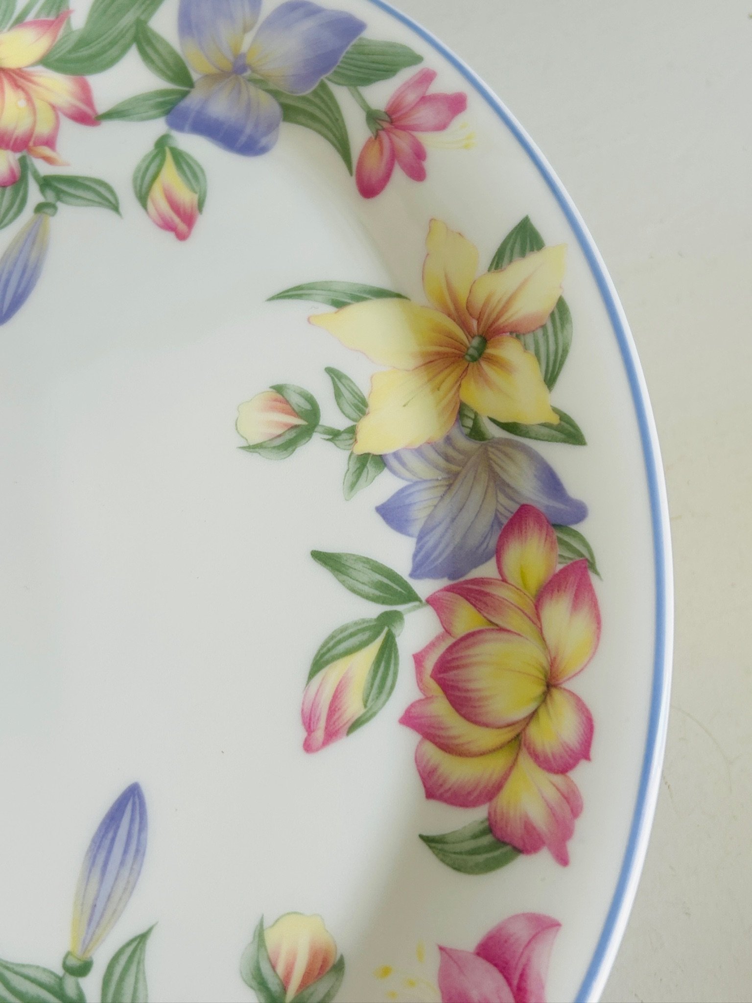 Close-up of the opposite side of the floral border on the oval platter, showing pastel blooms and buds against the white china background