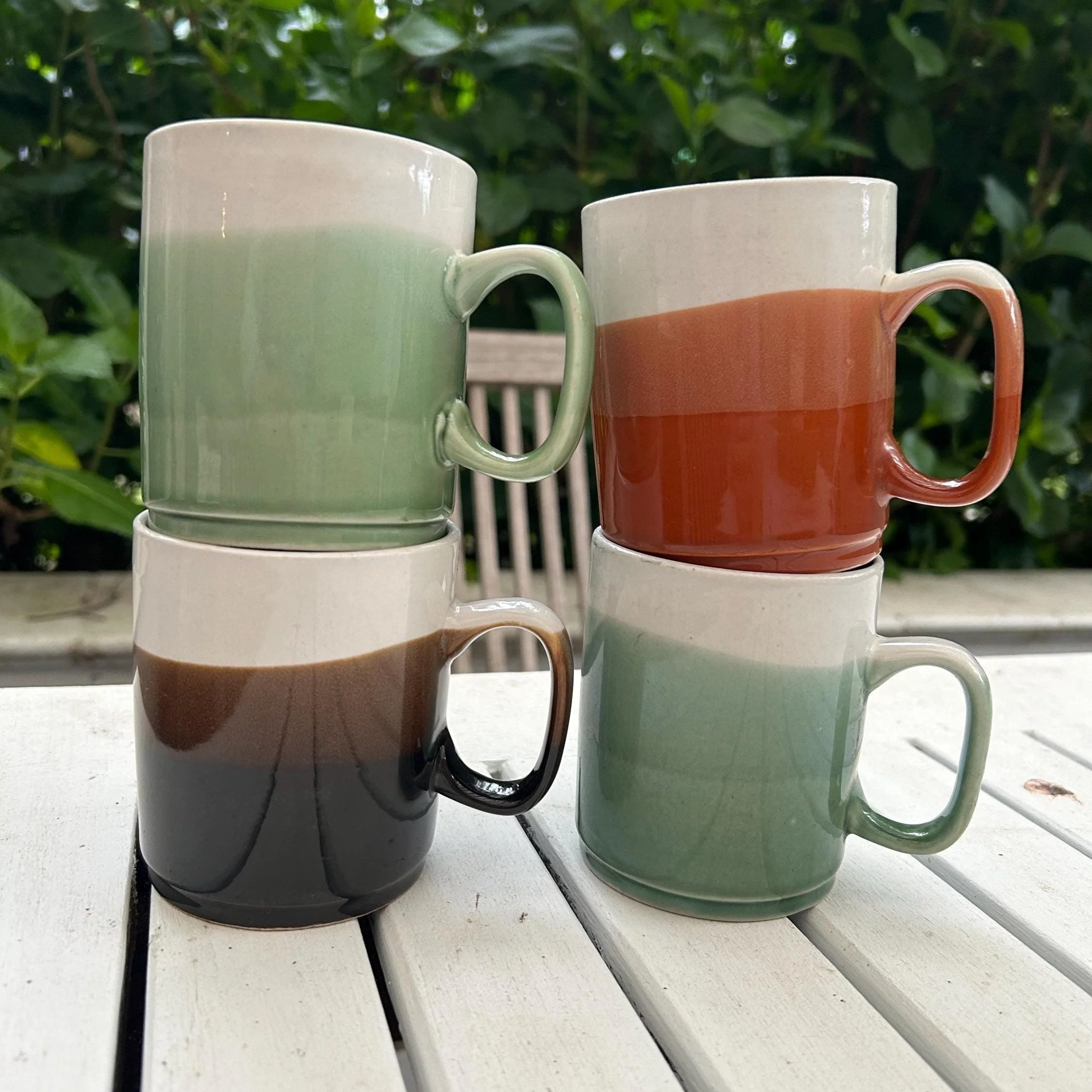 Set of 4 vintage ceramic mugs in classic 1970s tri-tone style. Earthy green, orange, and brown hues. Great for coffee lovers and retro kitchen collectors.